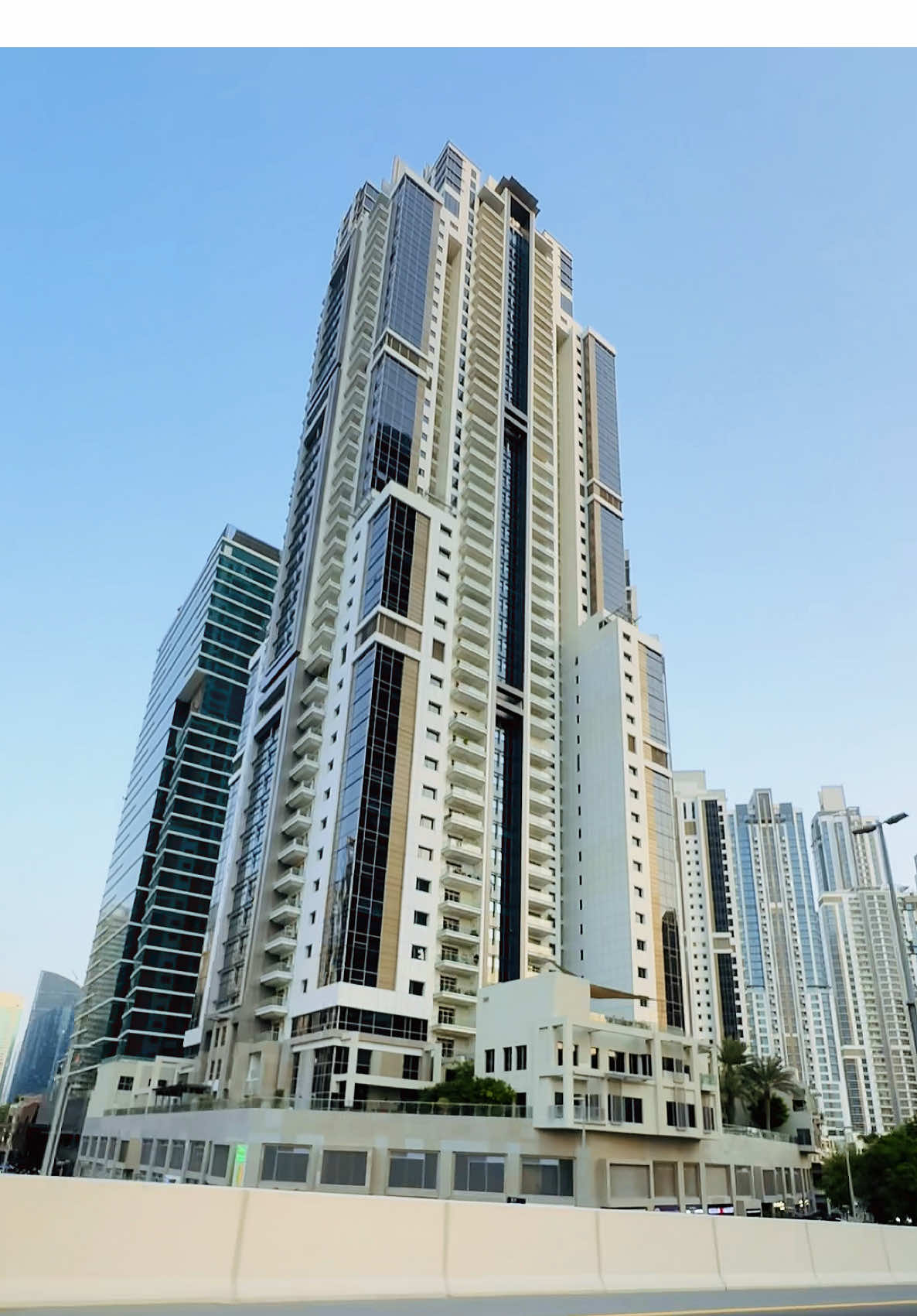 Part - 146 | “In the evening, the Executive Towers glow beautifully, creating a stunning view. I captured this moment while driving along Al A’amal Street.”  Place :  Bay Avenue in Business Bay is a community hub within the Executive Towers, offering shops, dining, services, and leisure spaces overlooking Bay Avenue Park, with easy access to Downtown Dubai and the metro. #businessbay #bayavenue #downtown #burjkhalifa #dubailifestyle 