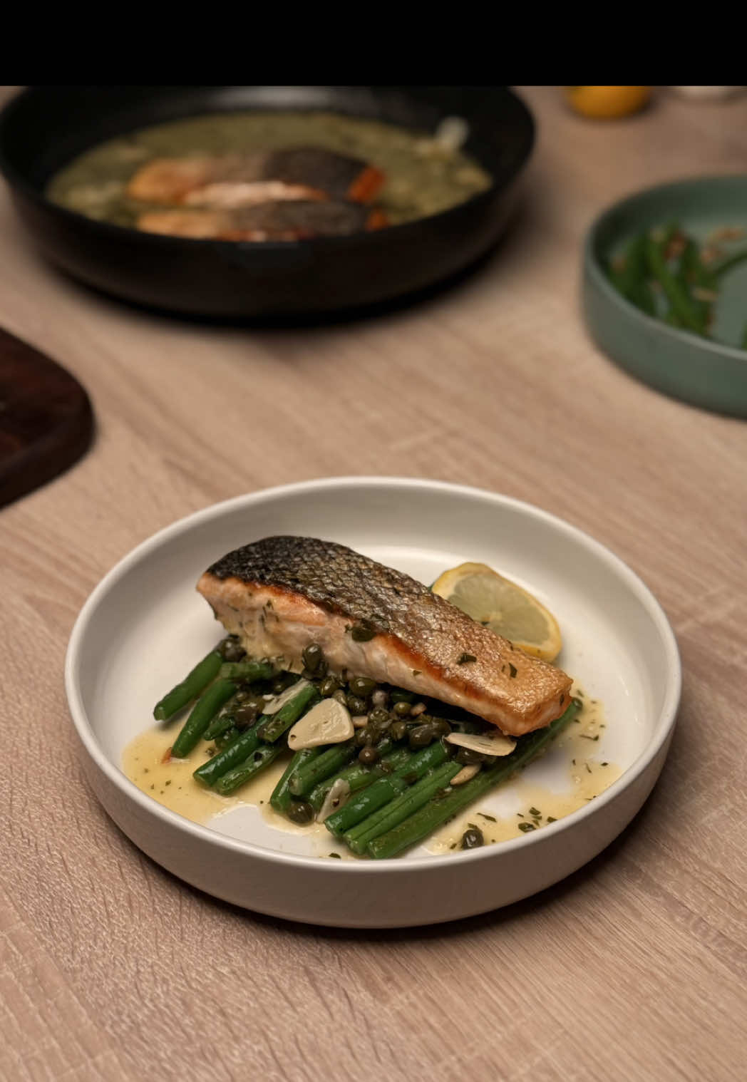 Crispy-Skin Salmon Piccata with Green Beans Amandine  Ingredients (2 servings): •	2 salmon fillets (160–180g each, skin on) •	olive oil •	salt, black pepper For the sauce: •	2 cloves garlic, thinly sliced •	80ml dry white wine •	2 lemons, filleted (segments diced) + a little juice •	1 tsp honey •	2 tbsp capers •	2 tbsp flat-leaf parsley, finely chopped •	50g cold butter, diced For the Green Beans Amandine: •	250g green beans, trimmed •	30g sliced almonds •	1 tbsp olive oil •	1 small shallot, finely chopped •	salt, pepper •	lemon zest, for finishing Instructions: 1.	Salmon: Pat the fillets dry and season with salt and pepper. Heat olive oil in a large pan over medium-high heat. Place salmon skin-side down and sear for 5–6 minutes without moving until the skin is golden and crisp. Flip and cook the flesh side for 2–3 minutes. Remove and keep warm. 2.	Sauce: In the same pan, sauté the garlic briefly without browning. Deglaze with white wine and let the alcohol evaporate. Add the diced lemon fillets and a little juice, then stir in the honey. Reduce for 2 minutes. Add capers and parsley. Take the pan off the heat and whisk in the cold butter cubes to emulsify. Season generously with salt and pepper. 3.	Green Beans Amandine: Blanch the beans for 3 minutes in salted water, drain and shock in ice water. In a pan, toast the almonds until golden and set aside. Add butter and olive oil to the same pan, sauté the shallot until soft, then toss in the beans. Season with salt and pepper, fold in the almonds and finish with lemon zest. 4.	Serve: Plate the salmon with the sauce spooned around (keeping the skin crisp) and add the green beans amandine on the side. #EasyRecipe #seafood #cooking