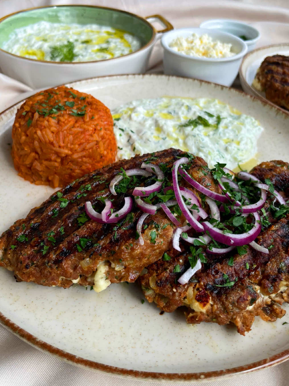 Bifteki mit Tzatziki & Tomatenreis🤍                                                 Zutaten für 2-3 Personen: Bifteki: - 400g Hackfleisch - 1/2 Brötchen - evtl. etwas Paniermehl, wenn der Teig noch zu weich ist! - 1 Zwiebel - 3 Knoblauchzehen - Bund frische Petersilie - 1 Ei, Größe S - Salz, Pfeffer - Oregano - Kreuzkümmel - Paprika Edelsüß - Vegeta, optional - ca. 100g Feta Tzatziki: - 300g Griechischer Joghurt - 1 Salatgurke - mind. 3 Knoblauchzehen - Frischer Dill - Olivenöl - Salz Tomatenreis: - 1 Zwiebel - 125g Langkornreis - 1 EL Tomatenmark - ca. 100ml Passierte Tomaten - ca. 250ml Gemüsebrühe > nochmal selbst schauen, ob ihr evtl. mehr Flüssigkeit braucht! - Griechische Gewürzmischung, optional - Salz - Petersilie - rote Zwiebel, optional Folgt gerne für mehr & lasst es euch schmecken!🥰🫶🏻 _________________ #bifteki #tzatziki #greecefood #rezepte #foryoupage 
