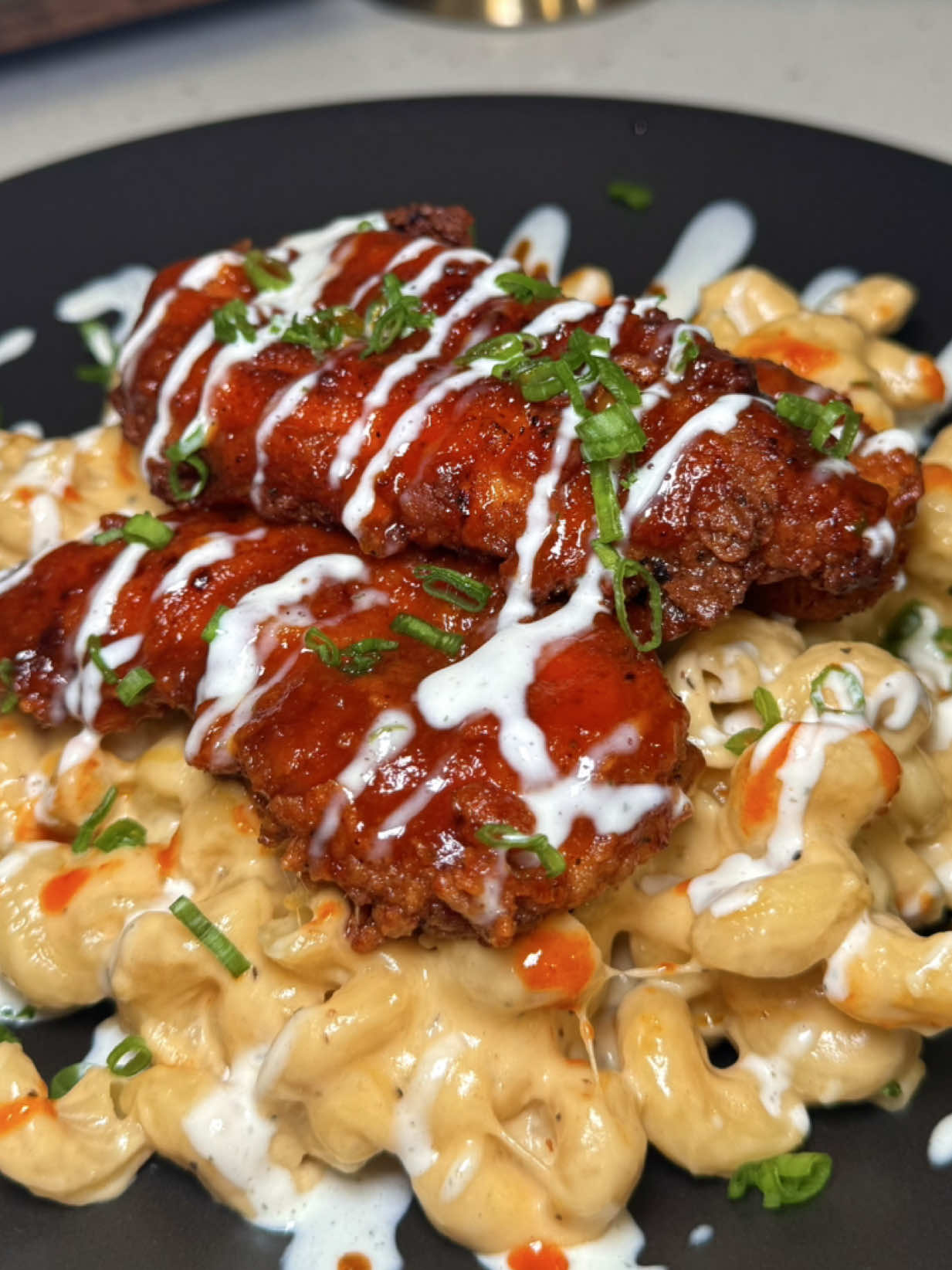 Hot Honey Chicken w/ Mac & Cheese 🔥🍯🧀🥵😋🤌🏻  Hot Honey Chicken Tenders 🐓 Ingredients For the Chicken: * 1 ½ lbs chicken tenders (or chicken breasts cut into strips) * ¾ cup buttermilk * ¼ cup pickle juice (from dill pickles) * 1 tbsp hot sauce (optional, for extra kick) * 1 cup all-purpose flour * Sprinkle of cornstarch * Smoked paprika * Cayenne pepper (optional for extra heat)  * Garlic powder * Onion powder * Salt * Black pepper * Slap ya mama  * Oil, for frying (canola or vegetable oil) For the Hot Honey Sauce: * ½ cup honey * Hot sauce (adjust to taste) * 2 Tbsp butter * Seasonings (smoked paprika, cayenne, garlic powder)  Instructions 1. Marinate the Chicken     * In a bowl, mix buttermilk, pickle juice, hot sauce and seasonings.      * Add chicken tenders, cover, and refrigerate for at least 30 minutes (up to overnight). 2. Prepare the Coating     * In a shallow dish, combine flour, cornstarch, smoked paprika, cayenne garlic powder, onion powder, salt, pepper, slap ya mama. Season liberally.  3. Dredge the Chicken     * Remove chicken from marinade, letting excess drip off.     * Coat in flour mixture, pressing to ensure the breading sticks.     * For the best results, place breaded chicken on a wire rack on a baking sheet, cover it loosely with plastic wrap, and refrigerate for at least 15-30 minutes. Before frying, let the chicken sit at room temperature for 15-30 minutes to avoid dropping the oil temperature and ensuring it cooks through without becoming greasy. 4. Fry     * Heat 2–3 inches of oil in a deep skillet or pot to 350°F.     * Fry chicken in batches until golden brown and cooked through (about 4-6 minutes depending on size).     * Place on a wire rack to drain excess oil. 5. Make the Hot Honey     * In a small saucepan over low heat, melt butter.     * Stir in honey, hot sauce, and your desired seasoning.      * Simmer gently for 2–3 minutes, stirring until combined. 6. Coat & Serve     * Drizzle or toss fried chicken tenders with hot honey sauce.     * Serve immediately or over mac & cheese.  MAC & CHEESE 🧀  (Inspired by Tini’s mac with some personal twists) Ingredients: * 1 lb corkscrew pasta (cavatappi) * 1 lb sharp cheddar cheese, shredded * 1 lb monterey Jack cheese, shredded * 1 lb smoked gouda cheese, shredded * 1 lb mozzarella cheese, shredded * ½–1 cup sour cream * 3 Tbsp butter * 3 Tbsp all-purpose flour * 1 (12 oz) can evaporated milk * 2–3 cups heavy whipping cream * 1 Tbsp Dijon mustard (or ground mustard/yellow mustard) * 1 splash hot sauce (optional, for balance) * 1 tsp garlic powder (to taste) * 1 tsp onion powder (to taste) * 1 tsp paprika or smoked paprika (to taste) * Salt & pepper (to taste) * Chicken broth (for cooking pasta) Instructions: 1. Prep the cheese:     * Shred all the cheeses. 2. Cook the pasta:     * Bring a large pot of salted water or chicken broth to a boil.     * Cook pasta until just under al dente (1–2 minutes less than package directions).     * Drain and stir in a scoop of sour cream while pasta is still warm. Set aside. 3. Make the cheese sauce:     * In a large saucepan, melt butter over medium heat.     * Whisk in flour and seasonings (garlic powder, onion powder, smoked paprika, salt, pepper). Cook for 2–3 minutes, stirring constantly, until bubbling and slightly golden.     * Slowly whisk in evaporated milk until smooth.     * Add heavy cream, whisking continuously.     * Stir in mustard and a splash of hot sauce.     * Let the sauce simmer gently for a few minutes until slightly thickened.     * Reduce heat to low, then add cheeses in small handfuls, whisking until melted and smooth.     * Reserve 1–2 cups of mixed cheese for topping. 4. Combine pasta and sauce:     * Stir cooked pasta into the cheese sauce until fully coated. 5. Bake:     * Pour mixture into a greased 9x13-inch baking dish.     * Layer with reserved cheese, sprinkling evenly on top.     * Bake at 350°F for 10–15 minutes, or until cheese is melted and bubbly. 6. Serve:     * Let rest for 5 minutes before serving for best texture. #fyp #cooking #dinner #viral #EasyRecipe