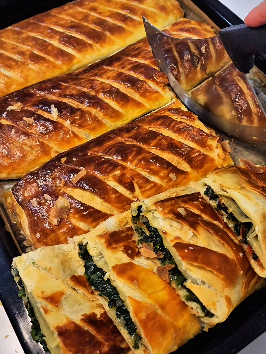 Ispanaklı börek tarifi ✅️ En sevdiğiniz emojilerle yorum yaparak destek olabilirsiniz 🌸 Hamuru için; 1.5 su bardağı ılık süt (300 ml) 4 yemek kaşığı yoğurt  1 adet yumurta  1 paket kabartma tozu (10 gram) 1 tatlı kaşığı tuz (10 gram) 5 su bardağı un (600 gram) Hamuru yağlamak için; 150 gram tereyağ (eritilmiş) 1 çay bardağı zeytinyaği (125 ml) Dolgusu için; 500 gram ıspanak  1 adet soğan  1 adet kırmızı biber  Yarım çay bardağı sıvıyağ (60 ml) Tuz, karabiber ve kırmızı toz biber  Üstü için; 1 adet yumurta sarısı   Hamur malzemeleri ile ele yapışmayan yumuşak hamur yoğuralım, hamuru 8 eşit bezeye bölerek 10 dakika dinlendirin. Dinlenen bezeleri 30 cm çapında merdane ile açın, ilk açtığınız yufkanin üzerine yağ  karışımını sürün kenarlarını katlayıp tekrar yağ sürün, ikinci bezeyide aynı şekilde açıp üzerine yağ sürelim, ilk hazırladığımız hamuru ikinci yufkanin ortasına yerleştirelim, kenarlarını katlayıp videodaki gibi yağ sürelim, bütün bezeleri aynı şekilde ikili İç içe katlayıp hazırlayalım, toplam 4 hamur olacak. Üzerini kapatıp 1 gece buzdolabında dinlendirin.    Aynı gün pişirmek istiyorsanız buzlukta 30 dakika mutlaka bekletmelisiniz yağın donması için.    İç harcı için ince doğranmış ıspanak, soğan ve kırmızı biberi geniş bir kaba alalım, üzerine sıvıyağ, tuz, karabiber ve kırmızı toz biber ekleyip elimizle güzelce karıştıralım.  Donan hamurları buzdolabından çıkartıp her birini dikdörtgen şeklinde açalım, çok ince açmaniza gerek yok, açtıktan sonra videodaki gösterdiğim gibi hamurun ortasına İç harcından bolca ekleyin, kenarlarını üst üste katlayın, 4 hamuruda aynı şekilde hazırlayıp tepsiye yerleştirin, üzerine yumurta sarısını sürüp keskin bıçakla çizikler atın, önceden ısıtılmış 180 derecede 30-35 dakika pişirin.  Afiyet olsun 🥰 #börek #hamurişi #tarif #çıtır #kolaytarifler 