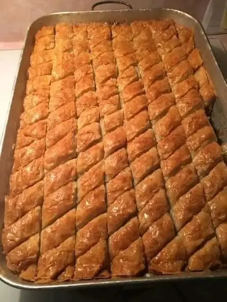 Golden Honey Baklava Ingredients : 1/2 pound chopped pecans 1/2 pound chopped walnuts 2-3 tbsp. ground cinnamon 1 pound package of Phyllo dough 1-1/2 cups butter, melted 2-1/2 cups honey 1 tsp. vanilla 1 tsp. grated lemon zest Mix nuts together in a large bowl and toss with the ground cinnamon. Set aside. Directions : Butter a 9×13 inch baking dish. Place 2 sheets of phyllo in the bottom of prepared dish. Brush generously with melted butter. Sprinkle 2-3 tablespoons of nut mixture on top. Repeat layers until all the nuts, butter, and phyllo are used. End with about 6 layers of phyllo on the top. If you still have some butter left, brush it over the top layer. Using a very sharp knife, cut through all layers of the baklava. Cut 3-4 sliced length-wise. Then make diagonal cuts to make diamond shapes. Bake in heated 350 degree oven for about 45 minutes, until golden and crisp. While baklava is baking, heat honey in a sauce pan until close to boiling. Stir in vanilla and lemon zest. When baklava is done baking, immediately pour the honey mixture over the top. Let cool completely in the pan.