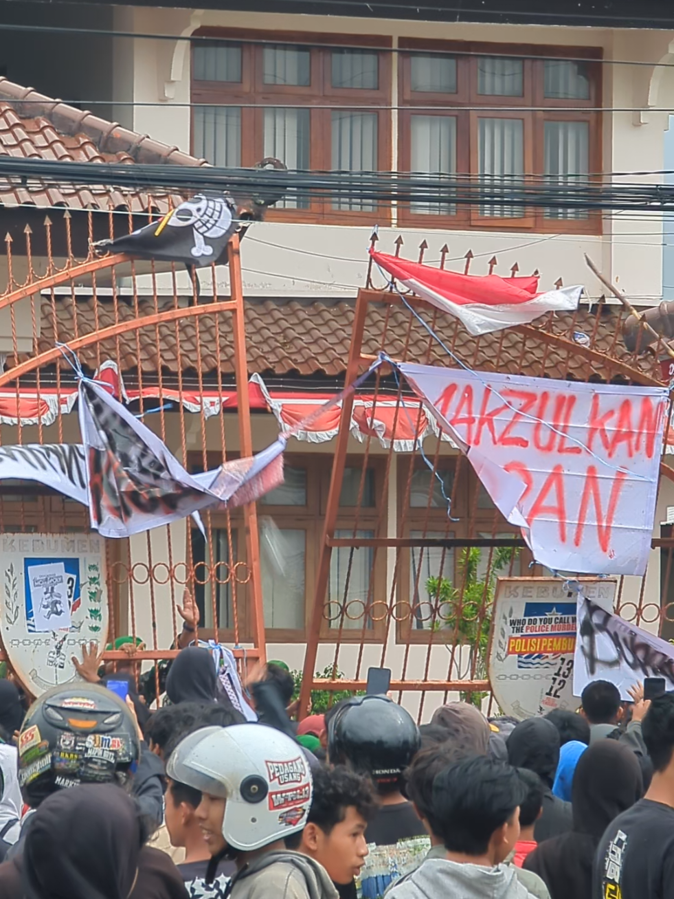 Pantauan di dua lokasi aksi, yaitu Polres dan DPRD Kebumen, menunjukkan perbedaan situasi yang mencolok. Area Polres tampak lengang, sementara di depan Gedung DPRD, sekelompok massa dengan pakaian dominan hitam terlihat sedang melakukan unjuk rasa. Mereka memasang beberapa spanduk di gerbang gedung, dengan tulisan-tulisan seperti “Makzulkan Gibran,” “Turunkan Pajak,” dan “Bubarkan DPR.” Situasi mulai memanas saat massa melempari halaman gedung DPRD dengan batu, botol plastik berisi air, dan bahkan tanaman yang dicabut dari pinggir jalan. Sejumlah aparat TNI terlihat bersiaga di gerbang untuk menjaga keamanan.