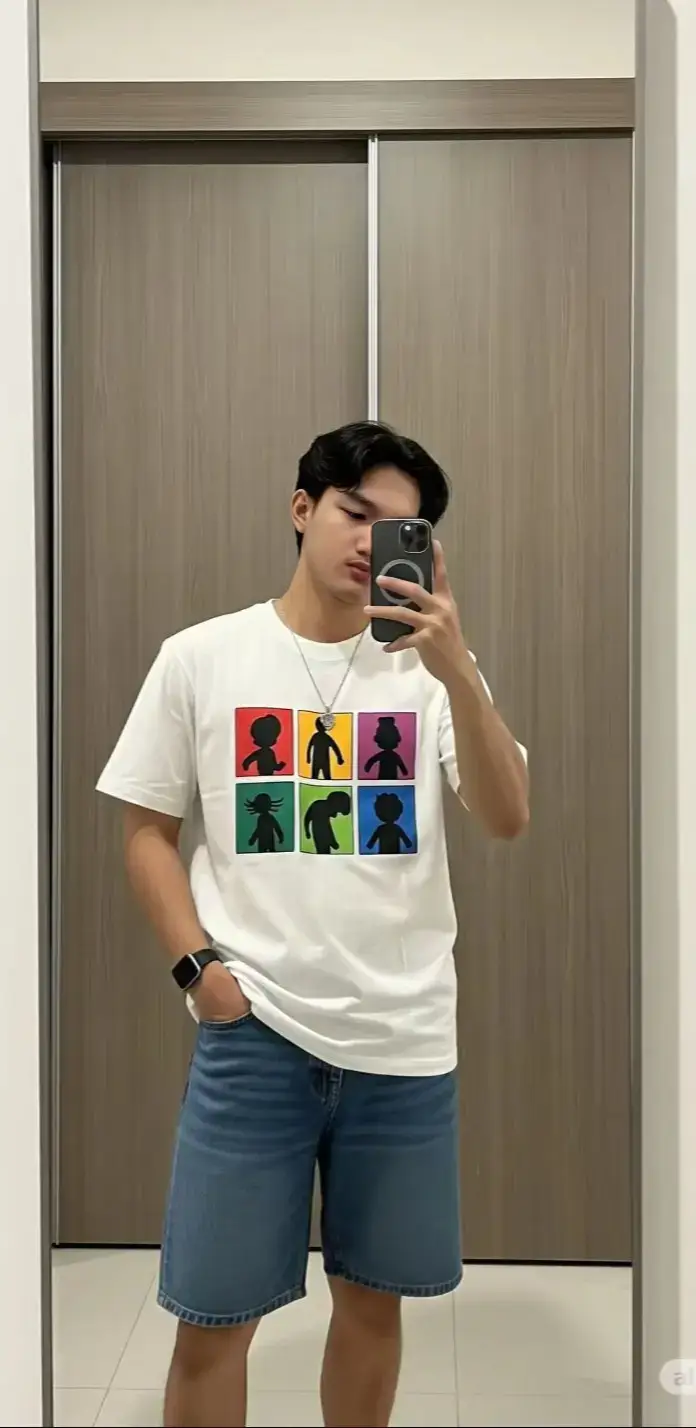 PROMPT : Seorang pria muda sedang berfoto selfie di depan cermin dengan menggunakan smartphone berwarna gelap. Ia mengenakan kaos putih bergambar enam kotak warna-warni (merah, hijau, biru, kuning, ungu, oranye) yang masing-masing menampilkan siluet karakter hitam. Kaos dipadukan dengan celana pendek jeans biru selutut. Ia memakai kalung perak dengan liontin bundar kecil serta jam tangan pintar berwarna gelap di pergelangan tangan kirinya. Pose santai dengan satu tangan memegang ponsel untuk memotret dan tangan lainnya masuk ke saku celana. Rambut hitamnya ditata rapi dengan gaya belah samping. Latar belakang ruangan minimalis dengan lantai putih bersih dan pintu geser kayu bernuansa cokelat muda. Suasana foto indoor dengan pencahayaan terang alami. #gemini #photolab #aiphotography #trending #googleai 
