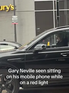 Gary Neville sits on his phone as he is stuck on a red light in central town in Manchester #zyxbca 