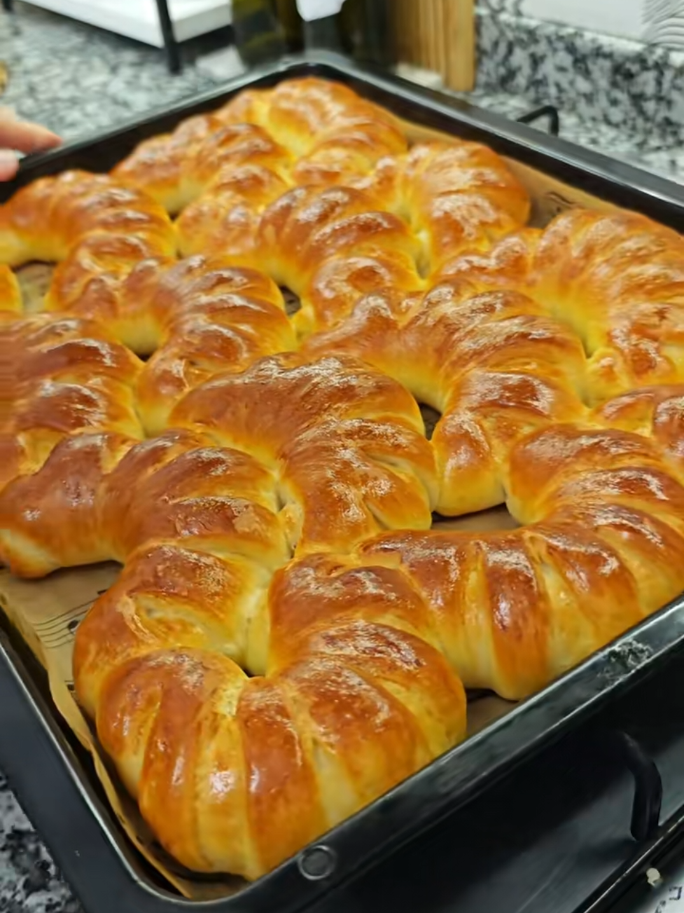 Şerit poğaça Malzemeler 2 su bardağı Süt 1 su bardağı Su Yarım su bardağı Sıvı Yağ 2 tatlı kaşığı Toz Şeker 1,5 tatlı kaşığı Tuz 1 paket Kuru Maya Un Üzeri için yumurta sarısı (aklarını hamurun içine ekleyin) Yapılışı 5 su bardağı unu yoğurma kabına alalım mayayı da ekleyip güzelce karıştıralım. Daha sonra sıvıları da ekleyip şekere ve tuzu da ilave edip güzelce hafif ele yapışan bir hamur elde edene kadar iyice yoğuralım. Unu ilk etapta 5 su bardağı kullandım daha sonra kıvam alana kadar azar azar ekleyerek yaklaşık 6 su bardağı un kullandım ama kullanılan unun markasına göre bu miktar değişiklik gösterebilir kontrollü ekleyin. Hamurun üzerine streç film ile kaplayıp bir saat mayalandıralım. Mayalanan hamur dan portakal büyüklüğünde parçalar koparıp bezelere ayıralım bu şekilde de 15 dakika dinlendirelim. Dinlenen her bir bezeyi elimizle güzelce açalım bir bıçak yardımıyla bir tarafına 8-9 tane çizik atalım. Diğer taraftan içe doğru kıvırarak çizik attığımız kısım üste gelecek şekilde rulo halinde sarıp ay şeklini verelim. Bütün bezeler bittikten sonra 15-20 dakikada tepsi mayası yaptırıp yumurta sarısı sürerek 180 derecelik ısınmış fırında alt üst kızarana kadar pişirelim. Deneyeceklere afiyet olsun +#pogaca #pogacatarifleri 