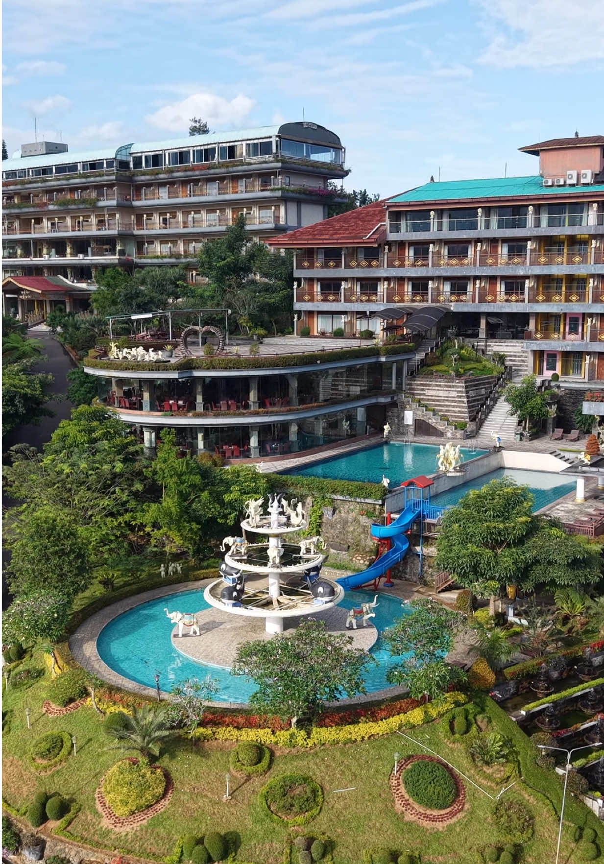 Hotel Seruni Hotel Seruni merupakan pilihan kami sekeluarga saat kami berada di sekitar kawasan Puncak Cisarua, Jawa Barat. Dengan paduan gaya arsitektur Bali dan Sunda membuat kami lebih nyaman menikmati sejuknya udara pegunungan di kawasan puncak. Lokasi : Jalan Nasional No.11, Tugu Utara, Cisarua, Bogor Regency, West Java 16750 Penampakan dari atas, dengan latar belakang Gunung Pangrango. Fasilitas hotel ini sangat baik, ada beberapa kolam renang, sampai bingung mau berenang dimana, waterboom, area bermain dan mini zoo. Pagi hari, jogging juga merupakan pilihan yang baik, bila males berenang. beberapa fasilitas mungkin terasa tua, kebersihan dan kenyamanan masih terjaga, serta pemandangan gunung yang indah.  Kekurangan yang dicatat adalah ketiadaan AC di kamar. Mungkin, pada awal berdirinya hotel, udara cukup dingin, tidak diperlukan AC, tapi menimbang makin ke sini, kawasan puncak semakin padat, dan udara pun tidak sedingin dulu. @Seruni Hotel  #serunihotel  #hoteldipuncak  #puncakbogor  #hotelpuncakbogor 