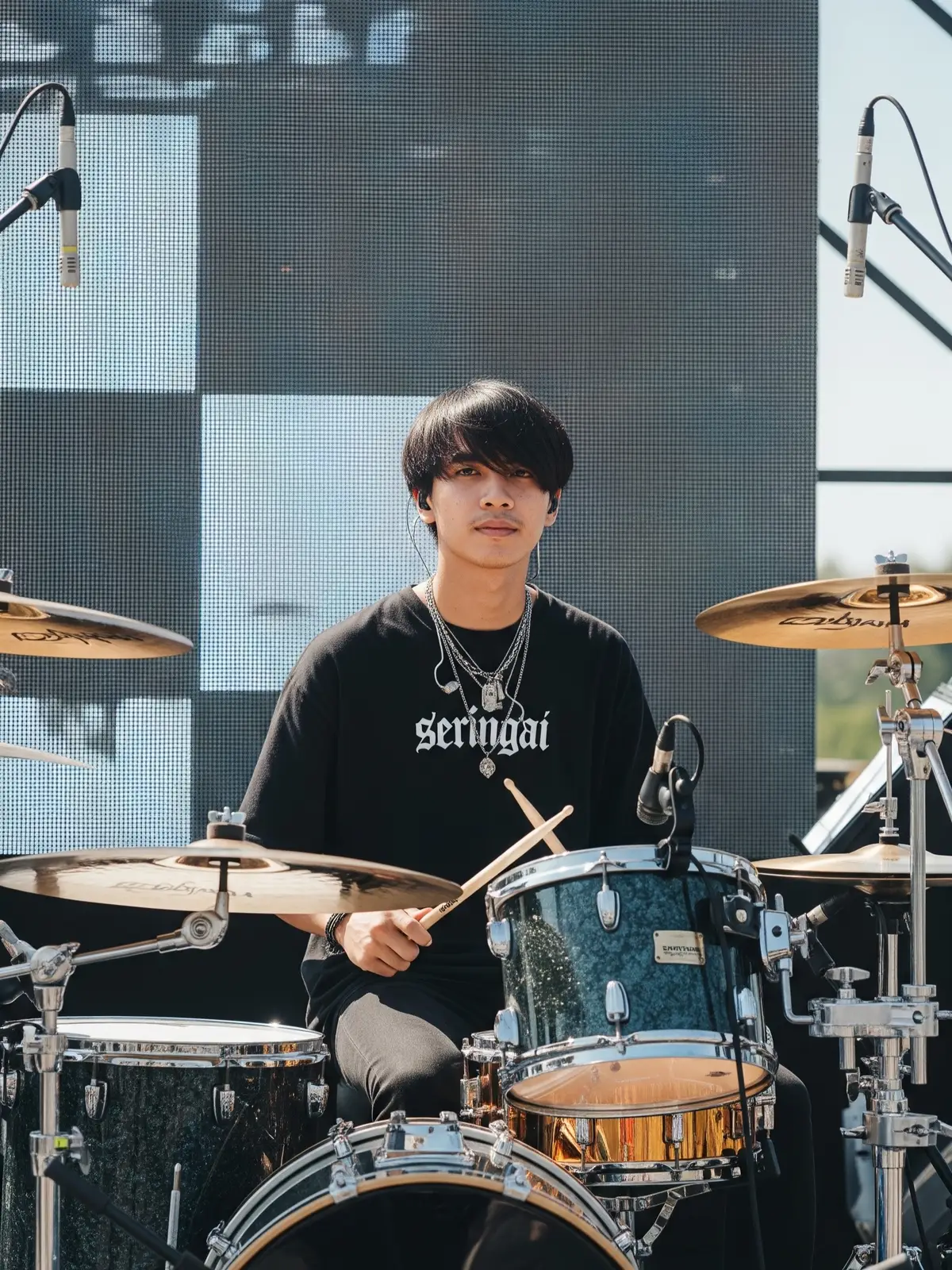 Prompt : Buatkan foto seorang pria muda indoensia dengan rambut middle part menutupi sebagian dahinya berwarna hitam. Dia terduduk di belakang perangkat drum. Dia mengenakan kaos hitam oversized dengan gambar tiga pria musisi hip-hop atau seniman (mungkin Run-DMC). Di lehernya terdapat beberapa kalung berlapis-lapis, dan di telinganya terlihat earphone in-ear monitor. Ekspresi wajahnya terlihat tenang atau serius menghadap kamera. kedua tangannya  memegang stick drum.  Latar Belakang dan Lingkungan: Latar belakang foto adalah panggung terbuka atau area pertunjukan, dengan cahaya matahari yang terang dari atas atau depan. Di belakang subjek, terdapat layar LED besar atau panel dengan pola kotak-kotak atau garis-garis samar yang membentuk desain geometris. Langit terlihat cerah, menunjukkan bahwa ini mungkin pertunjukan siang hari. Elemen Peralatan Musik: Di sekitar pria tersebut terdapat perangkat drum lengkap, termasuk:  Berbagai macam simbal (hi-hat, crash, ride) dengan warna keemasan yang mengkilap. Tom-tom dan snare drum yang terlihat kokoh. Beberapa mikrofon yang terpasang pada stand di sekitar drum kit, siap untuk merekam suara drum atau vokal. Terdapat juga beberapa stand mikrofon kosong atau untuk instrumen lain di sekitar area. Komposisi dan Pencahayaan: Foto ini diambil dari sudut pandang yang sedikit lebih rendah dari subjek, membuatnya terlihat lebih dominan di panggung. Pencahayaan sangat terang dan merata dari sinar matahari langsung, yang menyoroti detail pada wajah, rambut, dan pakaian wanita tersebut, serta kilauan pada simbal drum. Ada bayangan halus di beberapa bagian, tetapi secara keseluruhan foto ini terang dan jelas. Rasio Aspek 3:4 #prompt #fyp #ai #google #googlegemini #fyppage #vibes #fyppppppppppppppppppppppp #trend #chatgpt #drummer #drums #drum 