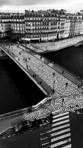 Jordane Saget is a contemporary urban artist based in Paris, best known for his signature trio of fluid, ornamental chalk or blanc de Meudon lines that gracefully animate the city’s streets and surfaces. Drawing inspiration from geometry, mathematics, and Tai Chi, Saget discovered that a sequence of three lines embodies a perfect balance of movement and harmony. He began placing this trio of lines in public spaces as early as 2015—on sidewalks, metro stations, billboards, and storefront shutters—creating ephemeral traces that catch the light and stir curiosity. Over time, he transitioned to using blanc de Meudon—an enduring form of chalk—to enhance the longevity and subtlety of his compositions, some of which endure for years and evoke emotional responses from passersby. Artist: @jordanesaget #art #painting #artist #streetart