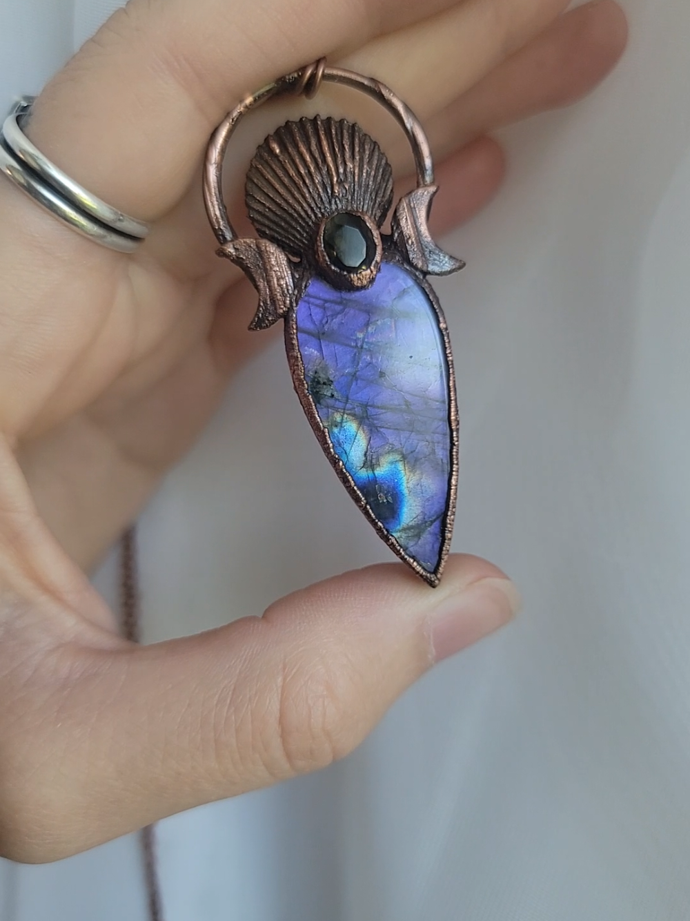 Let's talk about it for a second 💜🔮🍇 There was a huge craze of purple labradorite where it was nearly impossible to purchase purple labs without selling it immediately.  The reason it died down in my opinion is the production of cabochons and polished specimens that were just trying to get it out there as quick as possible without looking at the integrity of the flash, and more importantly the lay of it.  When I make necklaces with materials that have flash/chatoyance, I profile them so the flash is seen when worn (as it should be) or can easily be found.  This means I'm extra picky when it comes to labradorite and moonstone cabochons because while some can have the best flash ever, if its hard to find, I dont want it.  Or at the very least I disclose it. This beautiful full flash lab is finished with a real scallop shell I collected, and a faceted smokey quartz.  It's giving protective magic love vibes 💜 #purplelabradorite #labradorite #aphrodite #seashells #natureinspired 
