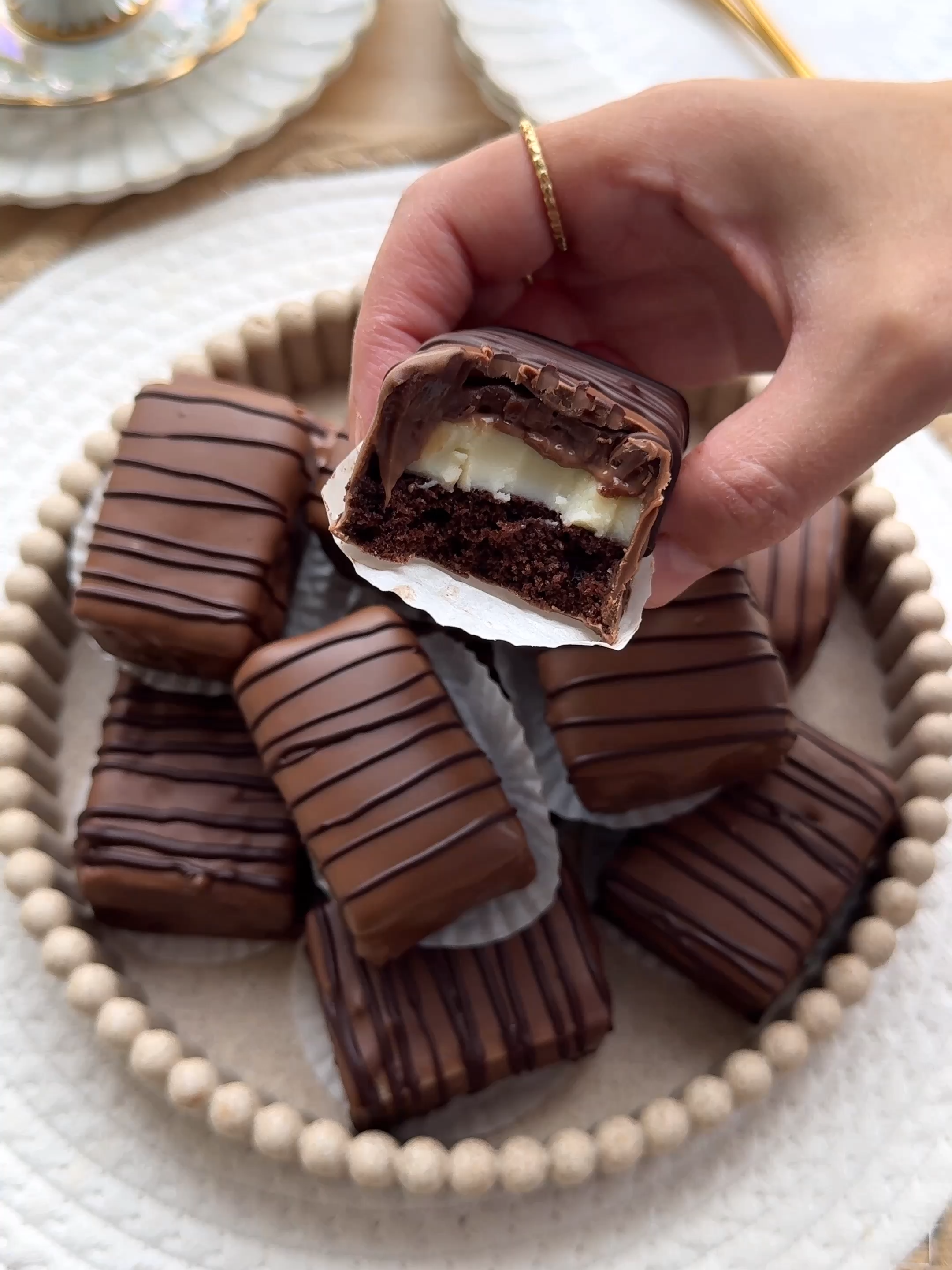 CHOCOLATE CREAM CAKES #food #recipe #chocolate #cake #cream #sweet #tasty #fy #fyp #foryou CAKE BATTER 2 eggs (medium) 100 g granulated sugar 8 g vanilla sugar (1 packet) pinch of salt 85 ml sunflower oil 100 ml milk 100 g all-purpose flour 25 g cocoa powder 5 g baking powder CUSTARD 2 egg yolks (medium) 75 g granulated sugar 8 g vanilla sugar (1 tbsp, or 1 tsp of vanilla extract) 45 g cornstarch 50 ml milk 450 ml milk (for cooking the cream) CHOCOLATE GANACHE 75 ml heavy cream  150 g milk chocolate COATING 300 g milk chocolate 50 g dark chocolate INSTRUCTIONS Break the eggs into a bowl and add the granulated sugar, vanilla sugar, and salt. Mix for 4–5 minutes until you get a light, airy, yellow mixture. Add the sunflower oil and milk and mix briefly. Sift the flour, cocoa powder, and baking powder and mix until smooth. Pour the batter into a greased baking pan (with parchment paper on the bottom). Bake the chocolate cake in a preheated oven at 175 °C (350 °F) for 10–15 minutes, or until done. Mix the egg yolks, granulated sugar, and vanilla sugar in a bowl for about 1 minute. Add the cornstarch and 50 ml milk, stirring until smooth. Bring the remaining 450 ml milk to a boil in a saucepan. Remove from heat and gradually add the egg mixture while stirring. Return the mixture to the saucepan and cook until it thickens, stirring continuously. Spread the custard evenly over the chocolate cake. Heat the heavy cream in a saucepan almost to a boil. Remove from heat and add the milk chocolate pieces. Let it stand for 1 minute, then stir until smooth. Let it cool slightly. Spread the ganache evenly over the custard. Cover the cake and refrigerate to set, preferably overnight. Melt the milk chocolate using a double boiler and pour into a small, deep bowl. Melt the dark chocolate using a double boiler and transfer to a piping bag. Cut the cake into pieces. Dip each piece into the melted milk chocolate and place on parchment paper.  Pipe thin lines of dark chocolate over each piece. Let the chocolate harden.