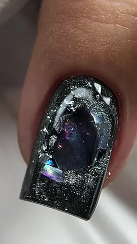 Pentru accest tutorial s-a folosit tipsuri natural square, polish black, scoică, painting cat eye silver și am sigilat totul cu no file clear. Rezultatul? Un efect de galaxie prețioasă care strălucește din orice unghi. 🌌💎 Ți-ar plăcea să porți acest look? 💅💫 #unghiigalaxie #cateyenails #nailartromania 