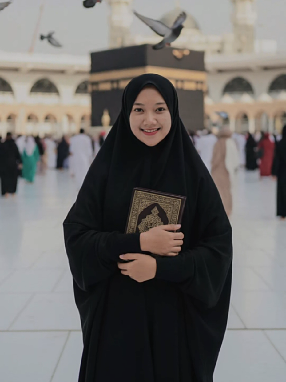 trimakasih prompt nya ,smoga mnjadi doa😅🤝🤲@Niia 🐝 :Buatlah foto ini menjadi foto seorang perempuan indonesia, berusia sekitar 25 tahun bb 53 kg tinggi 165 cm. menggunakan baju abaya serba hitam, hijab khimar hitam. Dia sedang foto berdiri di sekitar diarea masjidil haram. Dia berpose berdiri sambil pegang al quran berwarna coklat. ada beberapa orang di belakangnya yang sedang tawaf dan burung2 yang beterbangan. Buat semirip mungkin dan jangan rubah wajahnya. Buat senyata mungkin senatural mungkin. Jangan rubah wajahnya#trend #fyp #geminiai 