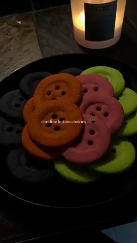 introducing my halloween baking series EPISODE 1: coraline button cookies 🪡🖤 i used @AngelSweets recipe with some personal tweaks!  1 cup of butter (2 sticks of unsalted) 1 cup of sugar 1 1/2 tsp of mexican vanilla extract 1 tsp of almond extract 3 cups of flour steps: *preheat oven to 350*  1. add room temperature butter and sugar into a large bowl and mix until everything is nice & fluffy.  2. add a room temperature egg + both extracts until both components are mixed fully into the dough.  3. slowly add in your flour (one cup at a time) until fully incorporated.  4. roll your dough into a ball & cut it into 4 pieces (one for each color) & fold each piece until you get your desired color.  5. roll your dough + place it into the fridge for 20 minutes 6. cut out your cookie, making sure to leave a smaller indent on each cookie to ensure a “button” look.  7. use whatever you have available (straw, cupcake decorator tip, etc) to create your button holes.  8. line a cookie tray with parchment paper & cook for around 8-12 mins. enjoy :) #coraline #buttoncookies #baking #halloweenbaking #fypシ 