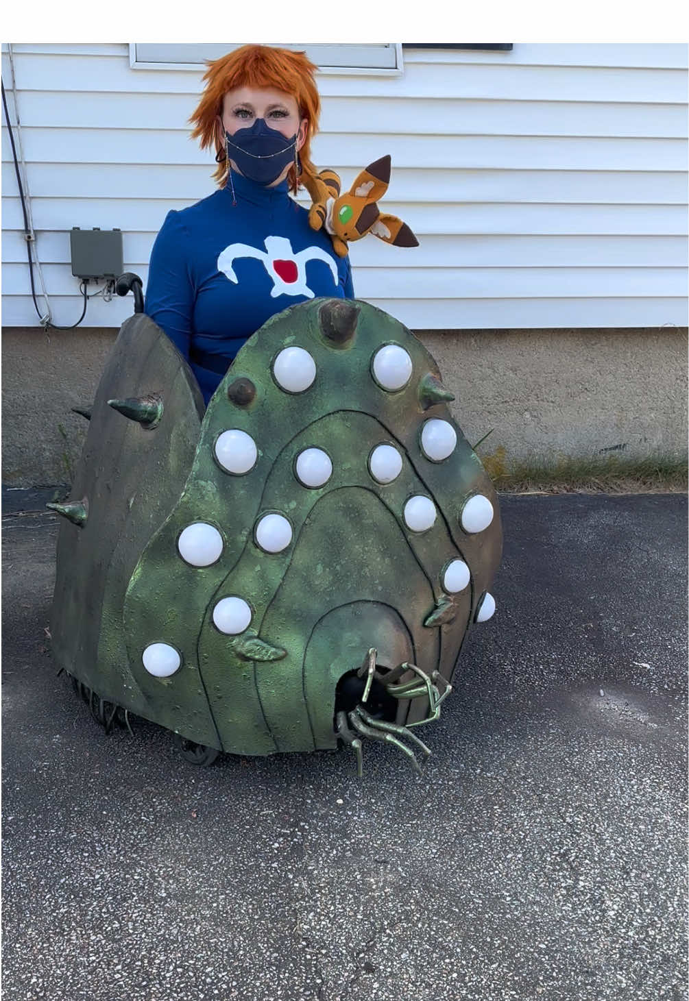 After last year‘s wheelchair, Howl’s Moving Castle cosplay I wanted to try another beloved Studio Ghibli film. This is my Nausicaä of the Valley of Wind cosplay with a wheelchair Ohmu.  I learned so many new skills making this cosplay, in particular working with EVA foam. The Ohmu is made of a hula hoop and bent fiberglass stakes covered in dremmel- edged EVA foam panels with foam clay accents and painted with Plasti Dip, drywall spray to texturize,  green copper color shifting paint, and a black wash to weather. The eyes are made up of LED lights, white spray, paint, and plastic Christmas ornaments. The legs are foam curling rods, bent in half and hanging on a wire amateur to allow for free movement. The mandibles are three sizes of foam curling rods and are attached to toe socks for extra life-like effect. The dress is pattern by Sew Anastasia made of cotton jersey with an appliqué of the royalcrest. The scenes were finished with an overcast, stitch, and the hems kept neat but flexible with a twin needle, straight stitch. The appliqué was traced onto Flexi Fuse, cut to shape and attached to the garment with a dense zigzag. Teto is made from a pattern by Sew Desu Ne out of felt and quilt batting. The appliqué was hand stitched to the body. The ears were stiffened with fusible interfacing. The body was sewn on machine, stuffed with quilt batting for extra firmness, and then finished with a ladder stitch. I made the mask chain and earrings from glass beads, jump rings, lobster, clause, and gold chain.  The wig was purchased online and steamed to remove creases and shininess. I love getting to bring one of my favorite characters to life and I’m looking forward to competing in the novice category in the Granite State Comic Con cosplay contest! #cos#cosplaye#wheelchairi#anime