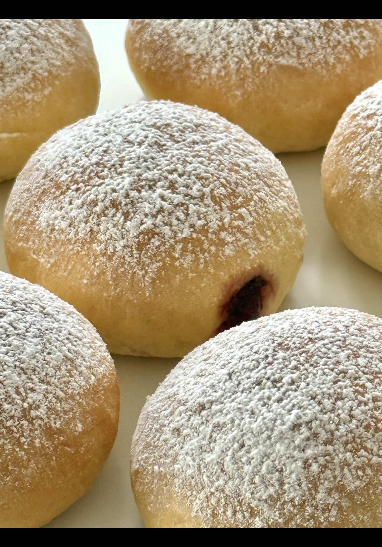Ad | Delicious Oven Berliner Recipe 🤍🍓 Soft, fluffy, and simply irresistible – these oven-baked Berliners are a delicious alternative to the fried version. Filled with sweet strawberry jam and dusted with powdered sugar, they’re a true treat.🤗🤍 📝 Ingredients (Makes about 8–9 pieces) 	 •	250 g all-purpose flour (2 cups) •	30 g sugar (2 ½ tbsp) •	1 tsp dry yeast (1 tsp) •	110 ml lukewarm milk (½ cup minus 1 tsp) •	40 g soft butter (3 tbsp) •	1 egg yolk (Size M) •	1 pinch of salt For filling & brushing: 	 •	about 150 g strawberry or raspberry jam (½ cup) •	20–25 g melted butter (about 1 ½ tbsp) •	plenty of powdered sugar 🤍 Instructions 	 1.	Dissolve the yeast with 1 tsp sugar in the lukewarm milk, let sit for 10 minutes. 	 2.	In a bowl, combine flour, remaining sugar, salt, egg yolk, and butter. Add the yeast mixture and knead for 8–10 minutes into a smooth, soft dough. 	 3.	Cover the dough and let rise for about 1 hour, until doubled in size. 	 4.	Divide the dough into 8–10 pieces, shape into balls, and gently flatten. Place on a baking tray lined with parchment paper, cover, and let rest for 30 minutes. 	 5.	Before baking, lightly brush the Berliners with some melted butter. 	 6.	Preheat the oven to 180 °C (350 °F) top/bottom heat. Bake for 15–18 minutes until golden. 	 7.	Right after baking, brush again with the remaining melted butter. Wrap the warm Berliners in a clean kitchen towel and let cool completely – this keeps them extra fluffy. 	 8.	Poke a hole in the side and pipe in jam with a piping bag. 	 9.	Dust generously with powdered sugar before serving. These oven-baked Berliners stay wonderfully soft and fluffy, with extra moisture from the butter. 🥰