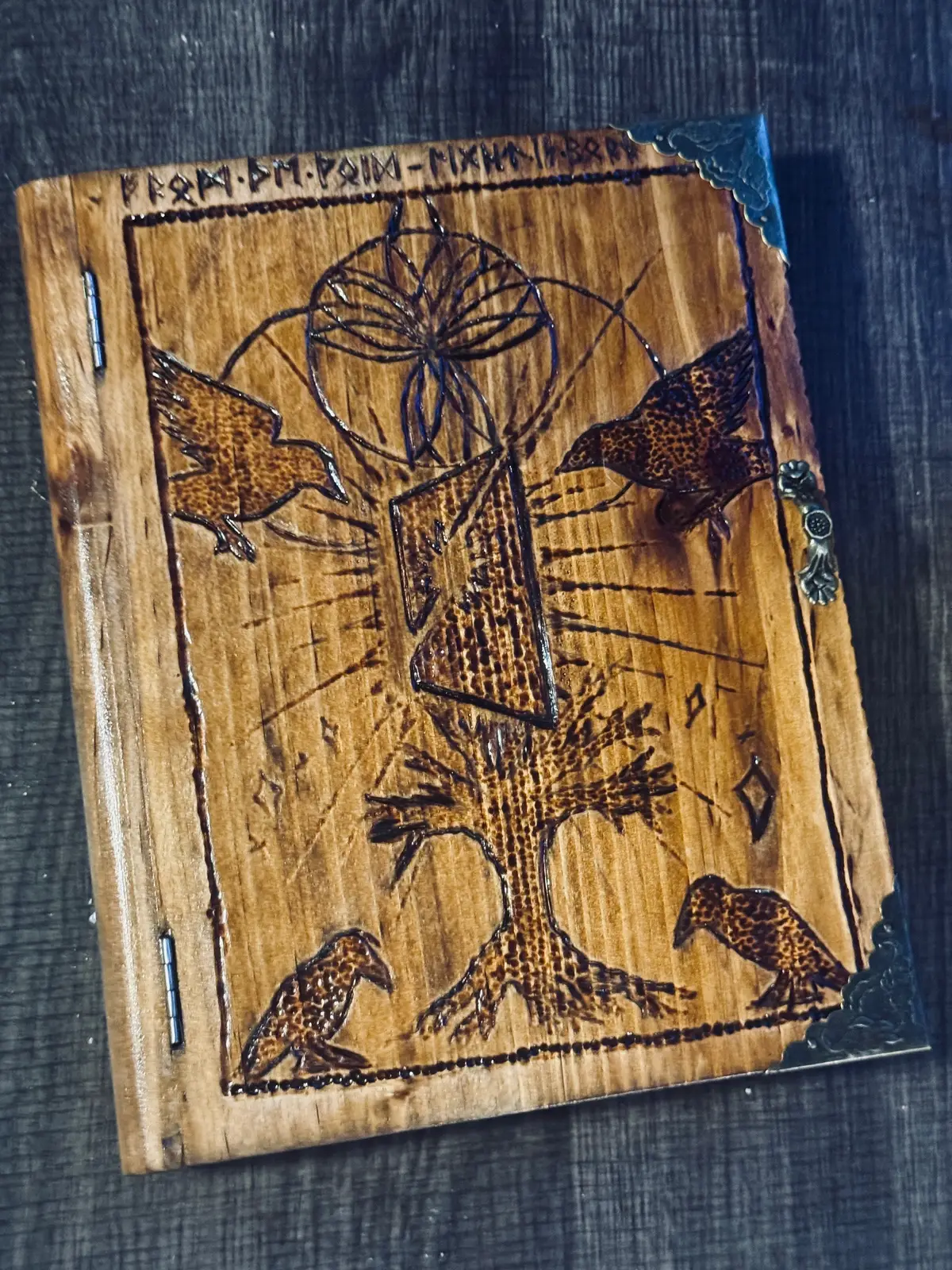 My first artistic wood burning design “Light of the Void” will be available this Friday ☀️  This piece carries the balance of mystical and grounded perspectives.  Using the ravens “Huginn and Muninn” the ravens of Odin in Norse mythology, this shows the different forms of thoughts and memories. You will see the tree of life at the bottom, extending up and rooted down. It reaches up holding the void tablet with light cracking through. This is supported by an entity (left to your interpretation) above the tablet.  Above, in elder Futhark runes you will find a message left for you to interpret. On the side we have a bind-rune representing light. On the outer trim representing the golden pages, you will find a hand mined quartz crystal. This is a piece of my journey that I give to you, the one who holds this piece.  Inside, there is a piece of old fashioned paper. Here, when you purchase, you can choose to leave it blank or you can message me and I can interpret something for you (possibly a dream) or write something with the intentions you provide. It is stained and sealed ready to last for years to come! ☀️ Looking forward to seeing who takes this piece home. I put a lot of myself into this one and I intentionally have it carry a specific energy as I burned it into existence. #artistsofinstagram #woodburning 