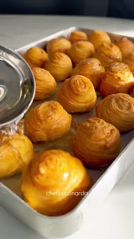 Katmer Bombası- KatmerBomb                                     Malzemeler Hamur İçin: • 300 g un (yaklaşık 2 su bardağı + 5 yemek kaşığı) • 100 g yoğurt (2 dolu yemek kaşığı) • 10 ml sirke (1 yemek kaşığı) • 20 ml sıvı yağ (2 yemek kaşığı) • 1 silme çay kaşığı tuz • 50 ml su (yaklaşık yarım çay bardağı, kontrollü ekle) • 1 yumurta İç Dolgu İçin (Mısırlı Nısastas): • 100 g Antep fıstığı veya fındık (toz hale getirilmiş) • 80 g tahin (yaklaşık 4 yemek kaşığı) • 60 g bal veya pudra şekeri (yaklaşık 3 yemek kaşığı) • 20 g tereyağı (eritilmiş, kıvamı yumuşak olmalı) • 40 ml süt (yaklaşık 2 yemek kaşığı, kıvamı ayarlamak için kontrollü ekle) Şerbet İçin: • 360 g şeker (yaklaşık 2 su bardağı) • 400 ml su (yaklaşık 2 su bardağı) • 3-4 damla limon suyu Yapılışı 1. Hamuru Hazırla ve Dinlendir Un, yoğurt, sirke, yumurta, sıvı yağ, tuz ve suyu karıştırarak yumuşak bir hamur yoğur. Hamuru 6 eşit bezeye böl ve bezelerin üzerini örtüp 30 dakika dinlendir. 2. İç Malzemeyi Hazırla İç dolgu için Antep fıstığı veya fındığı toz haline getir. Bir kaba tahin, bal veya pudra şekeri, eritilmiş tereyağı ve sütü ekleyip karıştır. Kıvamını ayarlamak için kontrollü bir şekilde süt ekleyebilirsin. 3. Hamuru Aç ve İçini Doldur Dinlenen hamur bezelerini birer birer al ve merdane yardımıyla olabildiğince ince aç. Açtığın hamurun yarısına hazırladığın iç dolguyu ince bir tabaka halinde sür. Hamurun diğer yarısını iç harcın üzerine kapat ve kenarlarını birleştir. Daha sonra bu dolgulu hamuru kendi etrafında rulo yap ve 3 cm genişliğinde dilimlere kes. 4. Katmer Bombalarını Oluştur Kestiğin hamur dilimlerini, fıstıklı-tahinli dolgu dışarıda kalacak şekilde yuvarlak bir top haline getir. Hamur topunu avucunun içinde hafifçe bastırıp yassılaştır ve fırın tepsisine diz. 5. Fırında Pişir Fırını 180 dereceye ısıt. Hazırladığın hamurları fırına ver ve üzerleri nar gibi kızarana kadar yaklaşık 15 dakika pişir. Fırından çıkan katmer bombalarını hafifçe soğuduktan sonra üzerine soğuk şerbeti gezdir. Şimdiden afiyet olsun!                              ———ENGLİSH——-                                Ingredients For the Dough: • 300g all-purpose flour (approx. 2 cups + 5 tbsp) • 100g yogurt (2 heaping tbsp) • 10 ml vinegar (1 tbsp) • 20 ml vegetable oil (2 tbsp) • 1 level tsp salt • 50 ml water (approx. half a tea glass, add gradually) • 1 egg For the Filling (Mısırlı Nısastas): • 100g ground pistachios or hazelnuts • 80g tahini (approx. 4 tbsp) • 60g honey or powdered sugar (approx. 3 tbsp) • 20g melted butter (melted, soft consistency) • 40 ml milk (approx. 2 tbsp, add gradually to adjust consistency) For the Syrup: • 360g sugar (approx. 2 cups) • 400 ml water (approx. 2 cups) • 3-4 drops of lemon juice Instructions 1. Prepare and Rest the Dough Mix the flour, yogurt, vinegar, egg, vegetable oil, salt, and water. Knead into a soft dough. Divide the dough into 6 equal balls, cover them, and let them rest for 30 minutes. 2. Prepare the Filling For the filling, grind the pistachios or hazelnuts into a powder. In a bowl, mix the tahini, honey or powdered sugar, melted butter, and milk. Add the milk gradually to achieve the desired consistency. 3. Roll Out the Dough and Add Filling Take each dough ball one by one and roll it out as thinly as possible with a rolling pin. Spread the filling mixture evenly over half of the rolled-out dough. Fold the other half of the dough over the filling and seal the edges. Roll this filled dough into a log and cut it into 3 cm slices. 4. Form the Katmer Bombs Take each dough slice and form it into a round ball, with the pistachio-tahini filling on the outside. Gently flatten the ball with your palm and place it on a baking sheet. 5. Bake Preheat your oven to 180°C (350°F). Bake the pastries until they are golden brown, for about 15 minutes. Once they come out of the oven, let them cool slightly, then pour the cold syrup over them. Enjoy your meal! If you'd like another recipe translated, feel free to ask.#tarif #food #sweet #tatlı #tatlıtarifleri 