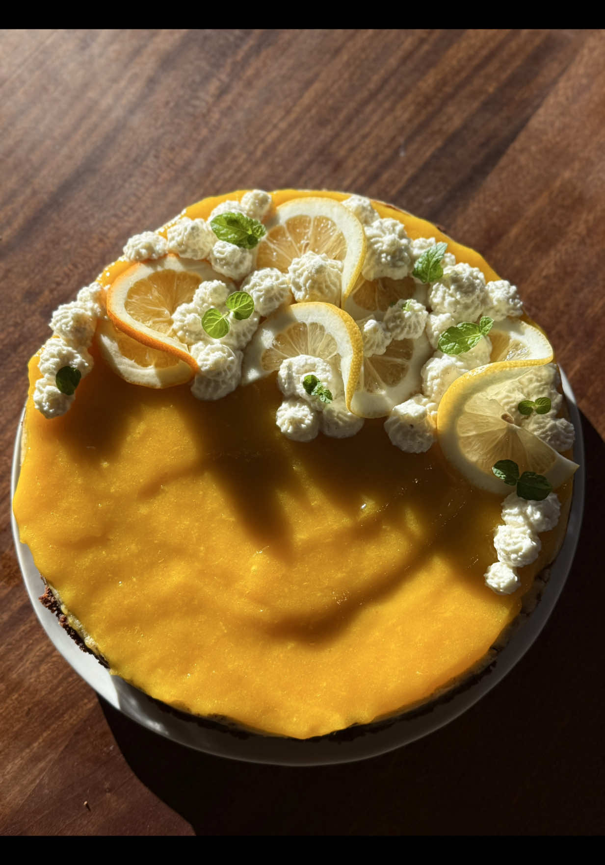 Lemon Ginger Cheesecake for the first day of Fall!🥳🍋🫚 Here’s how I made it 👇  Recipe For crust 1 2/3 cups crushed graham crackers 1/3 cup brown sugar 6 tbsp unsalted butter, melted 1/2 tsp ground ginger For cheesecake 16 oz cream cheese (softener room temp) 1/2 cup sugar 2 large eggs  1 1/2 tsp powdered ginger 1 tsp vanilla extract  Juice of 1 lemon Zest of 1 lemon 4 tbsp cream Lemon curd 4 egg yolks  2/3 cup granulated sugar Zest of 1 lemon 1/2 cup lemon juice 1.5-2.5 tbsp fresh grated ginger (taste as you go, it can take more than expected) 6 tbsp butter, softened and cut into chunks Whipped cream, lemon slices, and mint for garnish (optional) Preheat the oven to 350 F, then crush your graham crackers and mix them with the butter, powdered ginger, and sugar. Pour the mixture into a buttered 9-inch springform pan, then press it down all around so you have a nice crust (not too thick). Cook it in the oven for 6 minutes, then remove while you make the filling. In a bowl with electric mixer (or blender), whisk your cream cheese, then add the sugar and all remaining cheesecake ingredients. Mix until smooth, quickly blend if chunky. Pour the mixture over the crust, then fill a large baking pan with an inch or two of hot water, then place the cheesecake pan inside the water bath and bake for 45-60 mins until the middle is almost set but you see a slight wobble.  While the cheesecake is cooking, make the curd by adding the eggs, lemon juice, and zest to a cold pot, then put it on low and mix everything together. Add the butter chunks and ginger and continue to cook and mix on low until the mixture has thickened (it may seem like it won’t happen but be patient and adjust the heat slightly if necessary). Once thickened, remove from the pot. Once the cheesecake has cooled (you can cool it on the fridge), top it with a generous amount of curd. Decorate with sliced lemons, mint leaves, and whipped cream and enjoy! #lemongingercheesecake #baking #fallrecipes #dessert #lemoncurd