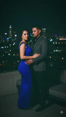 Texto Gemini : crea una sesión de fotos mi a y de mi esposo (sin modificar los rasgos faciales ) en la azotea de un edificio chic al anochecer, con el skyline de una ciudad iluminada como telón de fondo. Él con un blazer ajustado de un color oscuro (azul noche o gris antracita) sobre una camisa de seda negra, y yo con un vestido de cóctel ajustado, quizas con detalles metálicos o un corte asimétrico, en un color audaz como el borgoña o el azul cobalto. La iluminación sería más dramática, con sombras y luces que realzan nuestras facciones. La pose podría ser con él mirándome con intensidad, y yo con una sonrisa enigmática, ambos proyectando confianza y sofisticación. #gemini #geminiai #aiphotography #retratocinematográfico #fy 