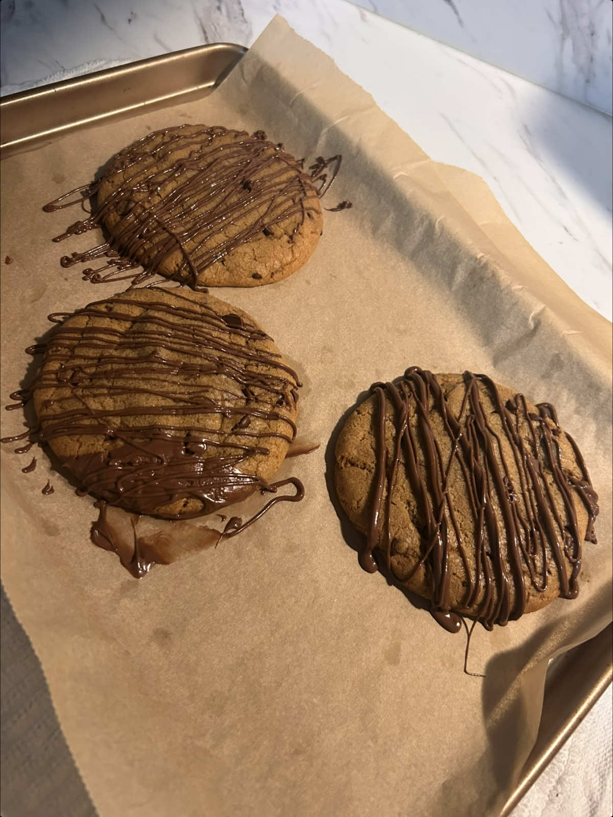 nutella stuffed chocolate chip cookies !    recipe:   1/2 cup butter, browned (113g) 1/4 cup granulated sugar (50g) 1/2 cup dark brown sugar, packed (100g) 1 large egg  1 tsp vanilla extract (5g) 1 1/2 cups all-purpose flour (190g) 1/2 tsp baking soda (3g) 1/4 tsp salt (1g) chocolate chips(measure with your heart idk, i used @Nestle Toll House ) 6 tbsp nutella(90g)(i used 3 for the cookies & the rest to drizzle.)  instructions- brown the butter & let cool slightly. in a bowl whisk together the browned butter & sugars until glossy. add the egg & vanilla and mix until combined. add in the flour, baking soda, and salt and fold gently then add chocolate chips and fold until the dough comes together. scoop dough balls, flatten slightly, place a frozen nutella scoop in the center, and roll it back up. bake at 350°f (175°c) for 11–13 minutes until golden on the edges but soft in the middle.( i made 3 big cookies & 6 small ones. the bigger ones cooked for 15-17 minutes. )    #nutella #chocolatechipcookies #cookies #fyp #baking  