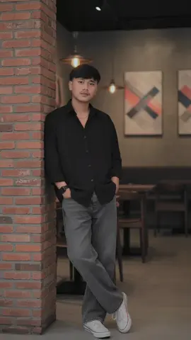 AI GEMINI PROMT Editkan foto ini tanpa mengubah wajah dan gaya rambutnya menjadi sedang duduk santai di kursi lipat hitam di area outdoor sebuah kafe malam hari bernama wallcoffe, dengan papan nama bercahaya putih di dinding bangunan modern minimalis. ia mengenakan kemeja oversized hitam dengan desain keren, dipadukan dengan celana baggy jeans oversized abu abu longgar, sepatu kets putih bersih dan sebuah jam tangan hitam modern. berpose santai sambil menghadap sedikit ke kiri kamera dengan ekspresi cool. di atas meja kecil di depan nya terdapat minuman dingin dalam gelas plastik bening dengan sedotan hitam serta sepotong kue cokelat di piring hitam. suasana Kafe terasa hangat dan nyaman, dengan lampu jalan bergaya klasik dan payung besar outdoor yang menaungi beberapa meja. latar belakang menampilkan pengunjung lain yang sedang mengobrol pria dan wanita, menambah kesan hidup dan sosial. lantai area duduk terbuat dari kerikil putih ke abu-abuan menciptakan nuansa kasual namun estetik. #baggyjeans #fyp #geminiai 