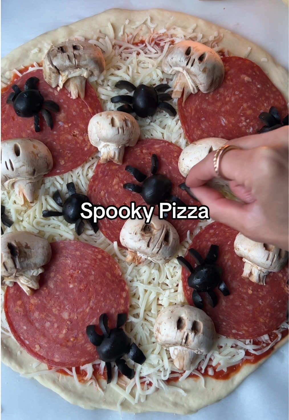 HALLOWEEN PIZZA NIGHT! 🍕💀🕷️ The perfect cozy date night or family dinner to enjoy with the fire going and a spooky movie on 🎃✨ INGREDIENTS: Pizza dough, homemade or store bought (I like Trader Joe’s in a pinch) Marinara sauce Mozzarella cheese, shredded Pepperoni  Mushrooms, whole Black olives, whole Preheat oven to 550 degrees or highest temp your oven will go!  On lightly floured parchment paper (I added too much flour in the video) spread pizza dough out forming a circle.  Add marinara, shredded mozzarella cheese, and pepperoni  Cut mushrooms in half, add eyes, nose, and little slits / cuts into mushroom stem for a bony neck.  Place mushroom skulls onto pizza.  Cut black olives in half and add to pizza, these are the spider bodies.  Cut more black olives into fourths long ways and then cut each slice perpendicular to make the legs.  Place 6-8 legs to form each spider on the pizza Bake for 8 - 10 minutes or until cheese is melted and done  #halloweenpizza #spookyfood #pizza #EasyRecipe   