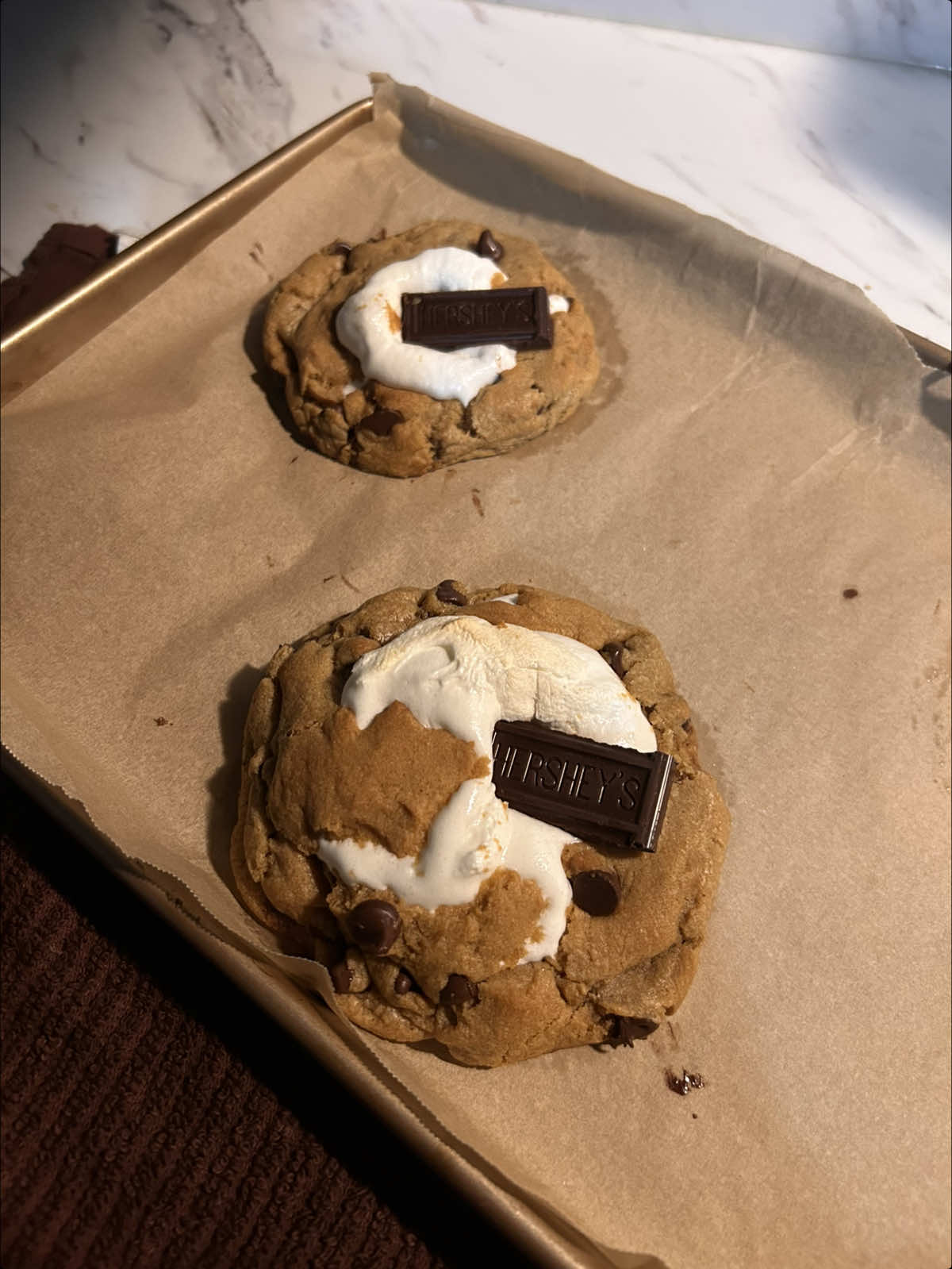 s’more chocolate chip cookies !! ik i said i was done but i love making these videos😅    here’s the recipe :   1/2 cup brown butter (113g) 1/4 cup granulated sugar (50g) 1/2 cup dark brown sugar, (100g) 1 large egg  1 tsp vanilla extract (5g) 1 1/2 cups all-purpose flour (190g) 1/2 tsp baking soda (3g) 1/4 tsp salt (1g) chocolate chips(measure with your heart idk, i used @Nestle Toll House choc chips also hersheys for the top & middle ) @jetpuffed marshmallows ( i used the jumbo ones :D ) & @Honey Maid graham crackers.  instructions- brown the butter & let cool slightly. in a bowl whisk together the browned butter & sugars until glossy. add the egg & vanilla and mix until combined. add in the flour, baking soda, and salt and fold gently then add chocolate chips and fold until the dough comes together. scoop dough balls, flatten slightly, place over your graham cracker & chocolate and form the dough around the marshmallow. ( i reccomend cutting the mallow in half if you’re doing smaller cookies) bake at 350°f for 11–13 minutes until golden on the edges.( i made 3 big cookies & 8 small ones. the bigger ones cooked for 15-17 minutes. )   #smores #cookies #baking #fyp #chocolatechipcookies 