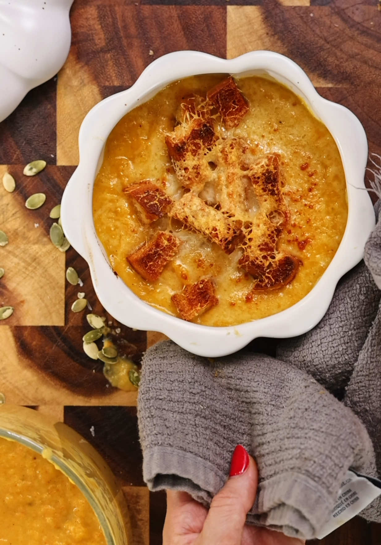 Last year, my butternut squash soup hit 70 million views — and this year, I’m back with a brand-new bomb combo. If French onion soup and butternut squash soup had a baby… Here is my 🧡 Fall in a Bowl 🍁 this year. Ingredients 1 medium butternut squash halved lengthwise and seeded 1 large carrot, peeled  1 head garlic, cloves peeled 3 large onions, thinly sliced 3–4 tbsp olive oil, divided 1 tsp paprika 1 tsp turmeric 1 tsp garlic salt Salt & freshly ground black pepper, to taste Pinch cayenne pepper (optional) 3–4 cups chicken bone broth 1 cup heavy cream Croutons: ciabatta cubes tossed with olive oil, garlic powder, salt Gruyère cheese, shredded Pumpkin seeds, for garnish 🔥 Step 1 – Roast the Veggies Preheat oven to 400°F (200°C). On a sheet pan, put squash, carrot, and garlic with olive oil, paprika, turmeric, garlic salt, salt, pepper, and cayenne. Roast 30–40 min until tender and caramelized. 🧅 Step 2 – Caramelize the Onions Meanwhile, heat 2 tbsp olive oil and melt 3 tbsp butter in a large skillet over medium-low. Add onions with a pinch of salt. Stir often and cook slowly 35–45 min, until deep golden brown and jammy — like for French onion soup.If they start to stick, splash in a little broth or water to deglaze and keep them silky. 🫕 Step 3 – Blend the Soup Scoop the roasted squash from its skin and add it to the pot with the carrot, garlic, and caramelized onions. Pour in 3 cups broth. Purée with an immersion blender until smooth and creamy. Stir in heavy cream and adjust seasoning. Add more broth if needed. Taste and season to perfection. 🍲 Step 4 – Bake With Toppings Preheat oven to 425°F (220°C). Ladle soup into oven-safe bowls. Top with croutons and a blanket of Gruyère. Broil for a few min until cheese melts. 🌻 Step 5 – Garnish & Serve Top with pumpkin seeds, drizzle with olive oil if desired, and serve piping hot. 🧡