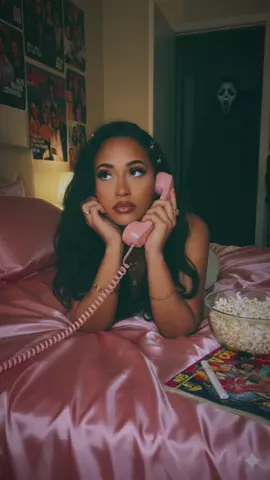 i am living for this trend 👻🖤 #ghostface #scream #googlegemini #whatsyourfavoritescarymovie  google Gemini AI prompt  Create a photo of me in a dreamy y2k style portrait of me laying on a shiny pink satin bedding as i hold a large 90s style chorded phone and in a thoughtful daydreaming pose her long wavy hair gold butterfly clips on each side. she wears delicate jewelry including dainty gold necklaces and accessories and gold chunky rings. the room behind her is girly and daydreamy with 90s style posters. her makeup is simple yet glamorous with brown lipgloss and brown lip liner. the photo should have a grainy 90s style to it with a light source like a lamp in a dimly lit room at night. a bowl of popcorn rests beside her near some 90s style magazines. A guy with ghostface costume should be behind her staring at her, his body should be dimly lit, and he should be standing in the doorway of a dimly lit hallway. the background behind he should be slightly dark and ominous
