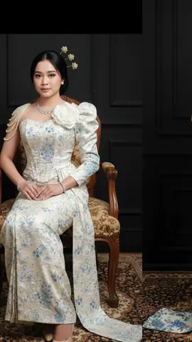 join trend gemini Al prompt: potret studio yang sangat realistis menggunakan wajah difoto ini harus mirip dan jangan ubah wajah dan karakter asli sesuai yang ada difoto.ubah foto ini menjadi wanita dengan mengenakan kebaya modern bernuansa putih gading dengan motif biru bergambar bunga dan burung merak.atasannya berbentuk korset vit body dengan bahu asimetris—satu sisi terbuka dihiasi untaian mutiara,sisi lain lengan puff dengan akses bunga putih besar.rok panjang lurus bermotif senada,ditambah kain gantung didepan dan pada pergelangan tangan.tampilan keseluruhan memberi kesan anggun,elegan dan mewah.foto diambil didalam studio dinding gelap elegan yang memberi kesan formal dan mewah.rambut disanggul modern dengan hiasan 3 buah susuk konde di sanggulnya,bagian rambut depan menjuntai di samping pipi kanan kiri.duduk dengan manja diatas karpet batik bermotif rumit.di lengkapi payung hias di sisinya.lengkapi dengan memakai kalung berlian dan gelang di kedua tangannya. #gemini #adatjawa 