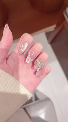 Spring vibe is fully loaded with these daisy press-on nails! 🌼 The sheer nude base is incredibly gentle, like a soft light filter on your fingertips. Hand-painted tiny daisies + 3D diamond-encrusted flower charms, every detail is meticulously crafted. French-style diamond edge adds a touch of luxury without being over-the-top. Skip the salon, get this fairy-like manicure in just 5 minutes! Perfect for dates, workdays, or vacations—every snap looks like a fashion editorial. Let your fingertips bloom with the beauty of spring! #PressOnNails #DaisyNails #SpringNails #NailArtInspo #glitternails💅 