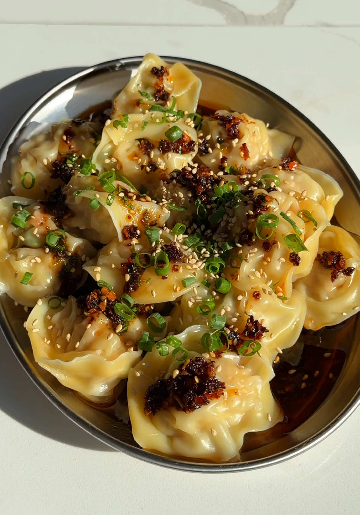 Pork & Prawn Wontons with Ponzu Sauce 🥟  Wonton Filling • 200g raw prawns  • 200g pork mince  • 3 cloves of garlic, minces • 3 green onions, finely sliced • 1 Tbsp Yum Yum Umami Seasoning  • 1 Tsp sugar  • 1/2 Tsp low light soy sauce  • Wonton Wrappers Ponzu Sauce • 2 Tbsp ponzu • 1 Tsp Soy Sauce  • As much @UmamiPapi Chilli Oil as your heart desires • Coriander  Method 1. Mix all of your wonton filling ingredients together 2. Throw the mixture down a couple of times to make the filling extra springy (thanks to @Chris Joe for the tip)  3. Assemble your wontons by filling with a tsp of filling in tbe middle of the wonton, wet each edge and fold into a triangle sealing each edge so there is no gaps. Wet the long ends of the wonton then wrap and seal to form your dumpling  4. Put wontons in your boiling water and remove once they float to the top (around 2-3 minutes max)  5. Combine your sauce ingredients together, place at the base of your plate, top with your wontons, then top your wontons with more chilli oil, spring onions, sesame seeds and enjoy 🫶🏼  #wontons #dumplings #EasyRecipe 