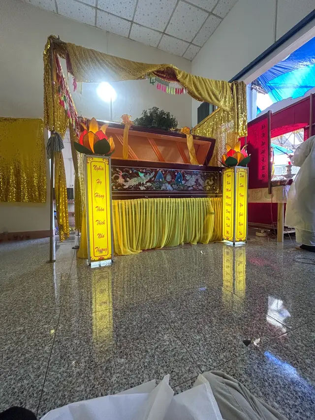 Trong căn nhà vàng nến hôm nay, tiếng kinh cầu như mỏng dần. Trên linh cữu phủ lụa, hoa sen đèn soi sáng hai bên dòng chữ “Nghĩa họ hàng thân thích nhớ thương”. Con ngồi đó, khăn tang trắng trên đầu, nhìn ngoại lần cuối mà lòng quặn thắt.  Ngoại đi rồi, nhẹ như một cơn gió chiều. Ngoại đi lúc bình minh vừa lên, chưa kịp ăn miếng cơm nóng. Không còn tiếng ngoại gọi: “Ăn cơm chưa con?” Không còn bàn tay gầy guộc chải tóc cho con mỗi lần về quê. Căn bếp từng nghi ngút khói, giờ chỉ còn lạnh.  Năm năm trước, ông ngoại đã đi trước. Ông bảo: “Bà ở lại sống tốt với con cháu nhen