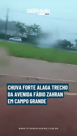 O temporal que atingiu Campo Grande nesta quinta-feira (30) causou transtornos na Avenida Fábio Zahran. Em poucos minutos, a água avançou sobre a pista e deixou um trecho da via parcialmente inundado. Registros feitos durante a chuva mostram a correnteza ocupando a ciclovia e uma das faixas destinadas aos veículos. O cenário obrigou condutores a diminuir a velocidade para atravessar a região com segurança. O ponto exige cautela, principalmente enquanto o nível da água não baixar completamente, já que o alagamento pode esconder buracos e outros obstáculos na pista.