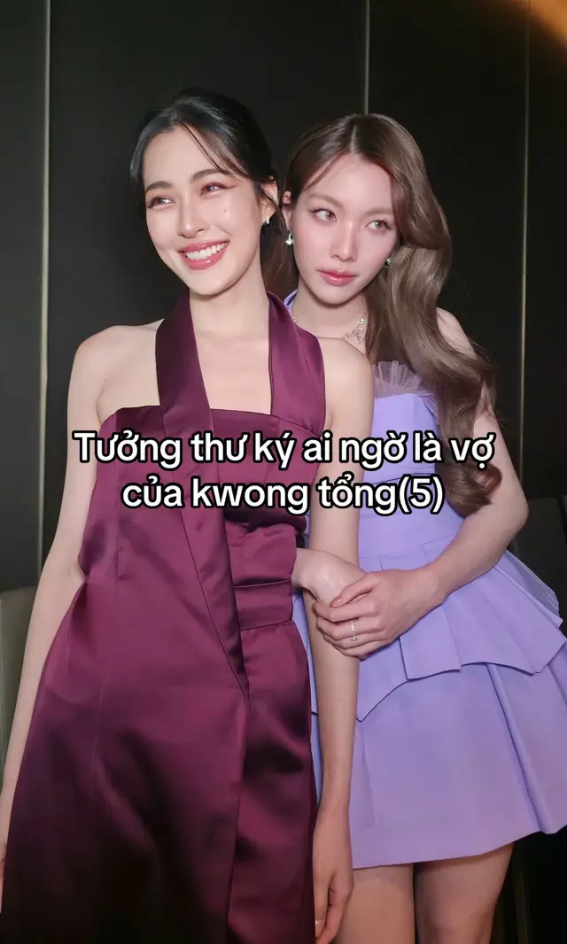 Chương 5: Thư Ký Mới Dám Ngắt Cuộc Họp Của Ling Tổng Ngày thứ năm. Mười giờ sáng. Phòng họp lớn của Ling Corporation đang im phăng phắc. Ling ngồi ở vị trí chủ tọa. Gương mặt lạnh nhạt. Ánh mắt khiến mấy vị quản lý bên dưới không ai dám lơ là. “Hạng mục này chậm ba ngày.” Ling đặt tài liệu xuống. “Tôi cần lý do.” Trưởng phòng dự án lập tức ngồi thẳng. “Ling tổng, bên đối tác có chút vấn đề—” Đúng lúc đó— Cửa phòng họp mở ra. Không gõ. Tất cả đồng loạt quay đầu. Orm đứng ngoài cửa, trên tay ôm một hộp thức ăn. Cả phòng: “…” Lại là cô thư ký mới đó! Orm nhìn quanh rồi rất tự nhiên bước vào. “Xin lỗi.” “Cho tôi mượn Ling tổng một chút.” Mấy vị quản lý suýt nghẹn. Mượn Ling tổng?! Đây là người chứ đâu phải tài liệu! Ling vốn đang lạnh mặt. Nhưng vừa thấy Orm— Ánh mắt lập tức dịu xuống. “Lại đây.” Orm bước tới cạnh cô. “Chồng chưa ăn sáng.” Ling hơi khựng. “Chị có uống cà phê.” “Cà phê không phải đồ ăn.” Orm đặt hộp bánh xuống trước mặt cô. “Ăn.” Cả phòng họp hoàn toàn im lặng. Ai cũng chờ xem Ling tổng sẽ phản ứng thế nào khi bị ra lệnh ngay giữa cuộc họp. Ling nhìn hộp bánh. Rồi nhìn vợ. “Đang họp.” Orm khoanh tay. “Em biết.” “Vậy còn vào?” “Chị đau dạ dày thì người chăm là em.” “Cho nên ăn trước.” Một vị giám đốc cúi đầu thật thấp. Không dám thở. Ling tổng ghét nhất bị làm gián đoạn khi họp. Lần này chắc chắn có chuyện. Nhưng ba giây sau— Ling chỉ khẽ thở dài. “Qua đây.” Orm lập tức đi tới. Ling kéo em ngồi xuống đùi mình. Cả phòng: “……” Lại nữa?! Orm mở hộp bánh, lấy một miếng đưa tới môi cô. “Há miệng.” Ling nhìn em. “Vợ.” “Hửm?” “Chị tự ăn được.” Orm lập tức rút tay về. “Vậy thôi.” Ling nhìn vẻ mặt đó. Chưa tới hai giây đã cúi xuống cắn miếng bánh trên tay em. “Được chưa?” Orm cong mắt. “Chồng ngoan.” Mấy vị quản lý: “……” Hôm nay đúng là mở mang kiến thức. — Orm vốn định cho Ling ăn xong rồi ra ngoài. Nhưng vừa đứng dậy— Ling giữ eo. “Đi đâu?” “Ra ngoài để chị họp.” “Ngồi đây.” “Em làm phiền.” “Không sao.” Orm cúi xuống ghé sát tai cô. “Chồng muốn ôm em đúng không?” Ling bình thản. “Ừ.” Orm lập tức cười. “Thừa nhận nhanh vậy?” “Vợ chị, chị ôm có vấn đề?” Orm hết cách. Đành ngoan ngoãn ngồi trong lòng cô. Cuộc họp tiếp tục. Ling một tay ôm eo Orm. Tay kia lật tài liệu. Giọng nói lại trở về vẻ lạnh lùng ban đầu. “Tiếp tục.” Trưởng phòng dự án cố gắng tập trung. Nhưng cảnh trước mặt thật sự quá khó thích nghi. Ling tổng vừa mới lạnh giọng với họ— Giây sau đã cúi xuống hỏi người trong lòng: “Muốn uống nước không?” Orm lắc đầu. “Không.” “Buồn ngủ?” “Không.” “Chán?” “Một chút.” Ling lập tức đẩy điện thoại của mình sang. “Chơi đi.” Cả phòng: “…” Đúng là cùng một người sao? — Cuộc họp kết thúc sau hơn bốn mươi phút. Mọi người vừa đứng dậy— Orm cũng định xuống. Nhưng Ling vẫn không buông. “Chồng.” “Hửm?” “Hết họp rồi.” “Ừ.” “Vậy thả em xuống.” “Không.” Orm bật cười. “Chị ôm đủ chưa?” Ling nhìn em. “Chưa.” Orm vòng tay qua cổ cô. “Vậy muốn ôm bao lâu?” “Cả ngày.” “Em còn phải làm thư ký.” Ling khẽ nhướng mày. “Em làm được gì rồi?” Orm lập tức kể. “Pha cà phê.” “Đưa tài liệu.” “Sắp lịch.” “Nhắc chị ăn sáng.” “Còn gì nữa?” Orm suy nghĩ. “Ngồi trong lòng chị?” Ling bật cười. “Cái đó làm tốt nhất.” Orm lập tức đánh nhẹ vai cô. “Chồng!” Ling giữ tay em lại. Sau đó cúi xuống hôn. Orm còn chưa kịp phản ứng đã bị kéo sát vào lòng. Nụ hôn chậm rãi. Dài hơn bình thường. Đến khi Orm bắt đầu đỏ mặt, Ling mới chịu buông. Orm tựa vào vai cô. “Đang ở công ty đó.” “Thì sao?” “Có người vào thì sao?” Ling bình thản. “Gõ cửa.” Orm phì cười. “Không phải chị ghét người khác vào không gõ cửa sao?” Ling vuốt nhẹ eo em. “Trừ em.” “Em được đặc quyền?” “Em có tất cả đặc quyền.” Orm lập tức ôm cổ cô chặt hơn. “Chồng chiều em vậy rồi sau này em hư thì sao?” Ling hôn nhẹ lên trán em. “Chị nuôi.” — Ngoài phòng họp. Tin đồn mới đã chạy khắp công ty. 【Thư ký mới ngắt cuộc họp để bắt Ling tổng ăn sáng.】 【Ling tổng không giận.】 【Còn kéo người ta ngồi lên đùi!】 Một nhân viên đọc xong chỉ biết lắc đầu. “Đây mà là thư ký bình thường thì tôi đi bằng đầu.” Còn Orm— Vẫn vui vẻ tiếp tục trò chơi của mình. Ngày thứ năm. Bí mật vẫn chưa bị vạch trần. Nhưng khoảng cách tới ngày cả Ling Corporation phát hiện— Có lẽ không còn xa nữa. — Hết Chương 5 —#lingorm 