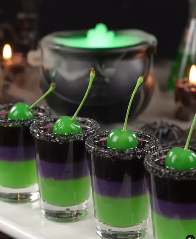 Frankenstein’s Lab Shots: Ingredients: 1/2 cup pineapple juice 1/2 cup vodka 3/4 cup blue curaçao 3 tablespoons grenadine Black sugar (for rimming) Green cherries (for garnish) Instructions: Prepare Glasses: Rim each shot glass with black sugar by dipping in pineapple juice first, then rolling in sugar. First Layer (Green): Mix pineapple juice with blue curaçao to create a neon green base. Pour into glasses and chill until slightly set. Second Layer (Purple): Carefully layer grenadine mixed lightly with curaçao to create a purple middle layer. Use the back of a spoon for a smooth pour. Final Layer (Black): Top with straight blue curaçao for a deep, dark finish. Garnish & Serve: Drop in a green cherry for a Frankenstein touch and serve chilled.