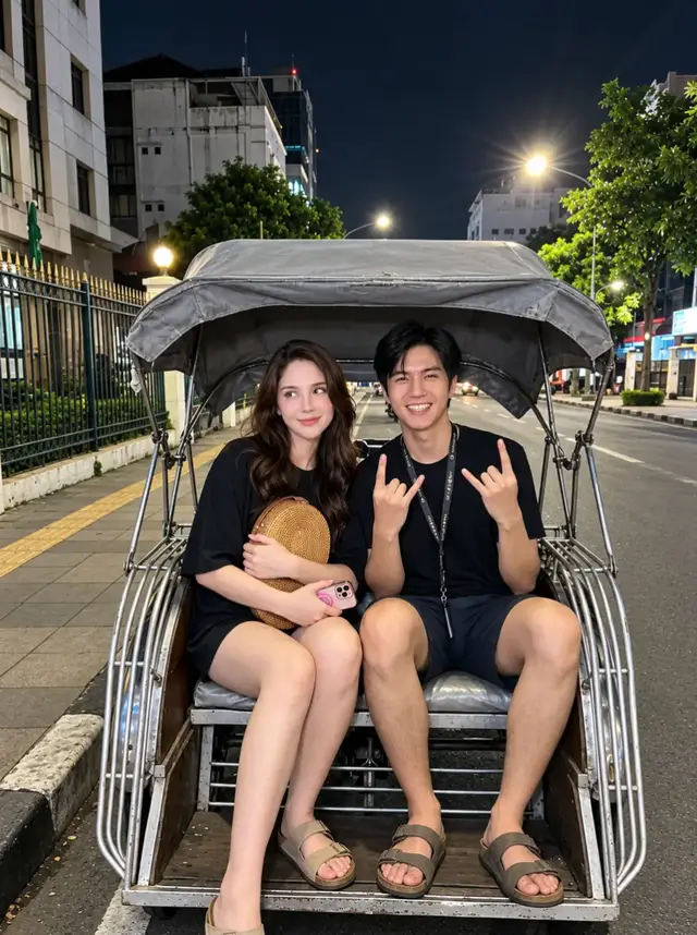 jalan jalan dulu @✨it's me✨❤️‍🔥 . Buat foto ultra-realistis sepasang anak muda yang duduk berdampingan di dalam becak motor tradisional di pinggir jalan pada malam hari. Wanita berambut hitam panjang terurai mengenakan kaus hitam oversized dan celana pendek gelap. Ia duduk santai sambil memeluk tas anyaman rotan berbentuk oval berwarna cokelat muda dan memegang smartphone dengan casing merah muda. Ekspresinya manis dengan senyum tipis sambil memandang ke arah kiri. Pria di sebelahnya mengenakan kaus hitam, celana pendek gelap, dan tali lanyard di leher. Ia tersenyum lebar ke arah kamera sambil mengangkat kedua tangan membentuk gestur rock-on. Keduanya mengenakan sandal kasual. Becak memiliki rangka logam berwarna perak, tempat duduk penumpang, dan atap kanvas abu-abu kusam. Latar berupa jalan perkotaan malam hari dengan bangunan, pagar besi, pepohonan, kendaraan, serta lampu jalan terang yang menghasilkan pantulan cahaya dan sedikit efek flare. Komposisi vertikal 3:4, sudut pengambilan sedikit tinggi, menampilkan kedua subjek dari kepala hingga kaki dan sebagian besar becak. Pencahayaan malam yang realistis dengan perpaduan cahaya lampu jalan berwarna hangat dan bayangan alami, suasana candid, santai, dan autentik. Diambil menggunakan kamera utama smartphone, RAW photo, HDR, resolusi 8K, ultra-photorealistic, detail wajah dan kulit alami, helai rambut tajam, tekstur kain dan anyaman rotan realistis, anatomi tangan dan kaki akurat, detail logam becak jelas, warna natural, dynamic range tinggi. Hasil harus tampak seperti foto asli, bukan AI atau CGI. #geminiai  #couple  #fyp  #4u 