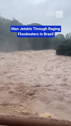 After heavy rainfall, a person rides a jet ski through the churning, muddy floodwaters of the Piracicaba River in Piracicaba, Brazil.
